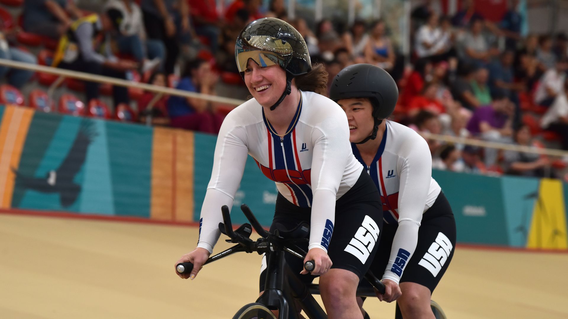 Photo of two athletes riding a tandem bicycle on a race course