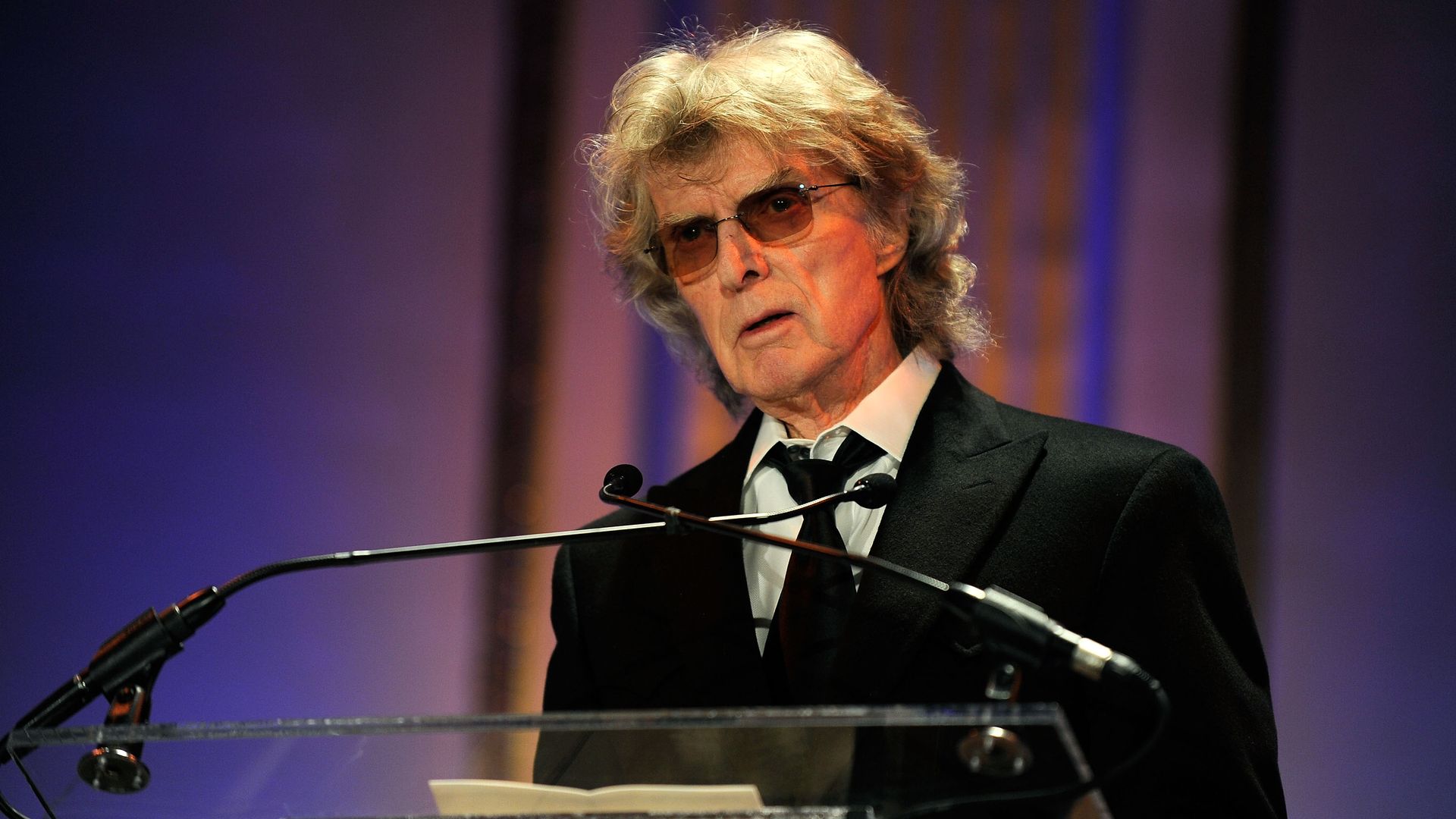 In this image, Don Imus stands at a podium