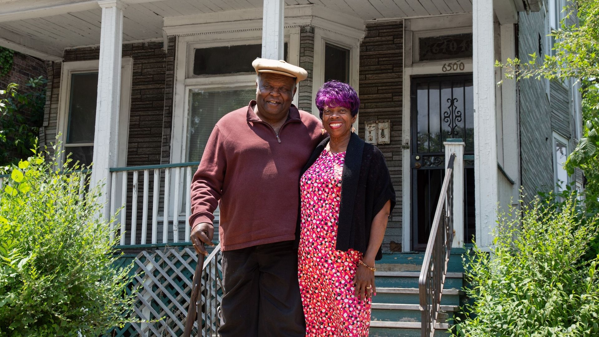 Photo of two people standing in front of a house 
