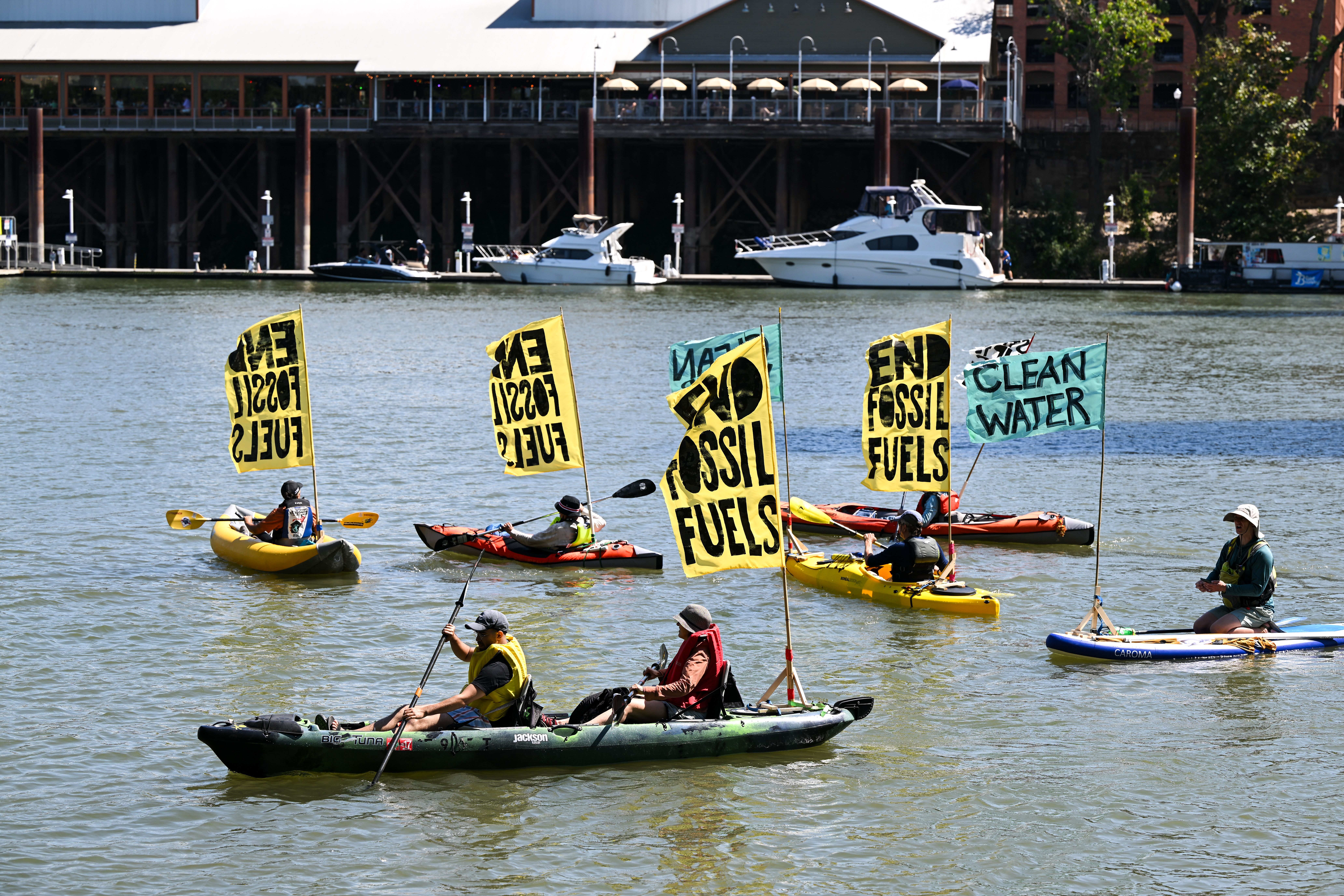 Activists kayak on the river with flags that say ''End Fossil Fuels'' as hundreds of climate change activists are gathered at Old Sacramento Waterfront near the Tower Bridge, to protest global climate change and fossil fuels, in Sacramento, California, United States on September 17.