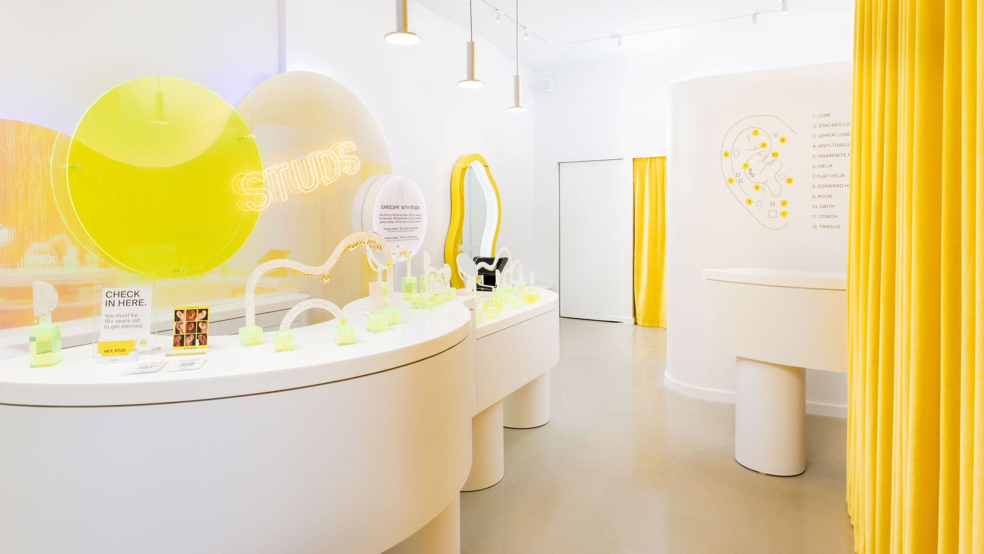 Photo of a white room with earrings on display. 