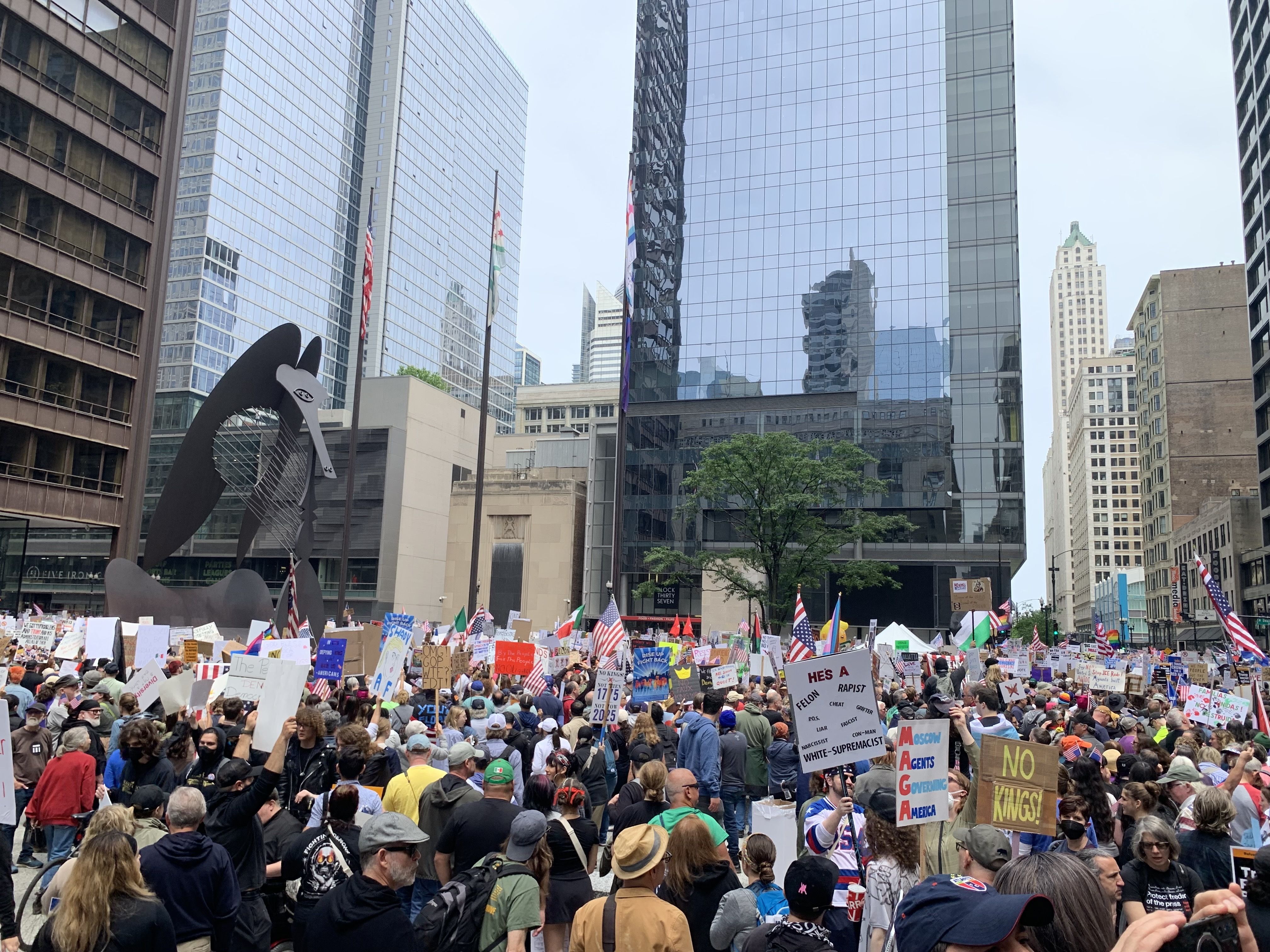 Protesters fill up a plaza with signs and march on a street. 