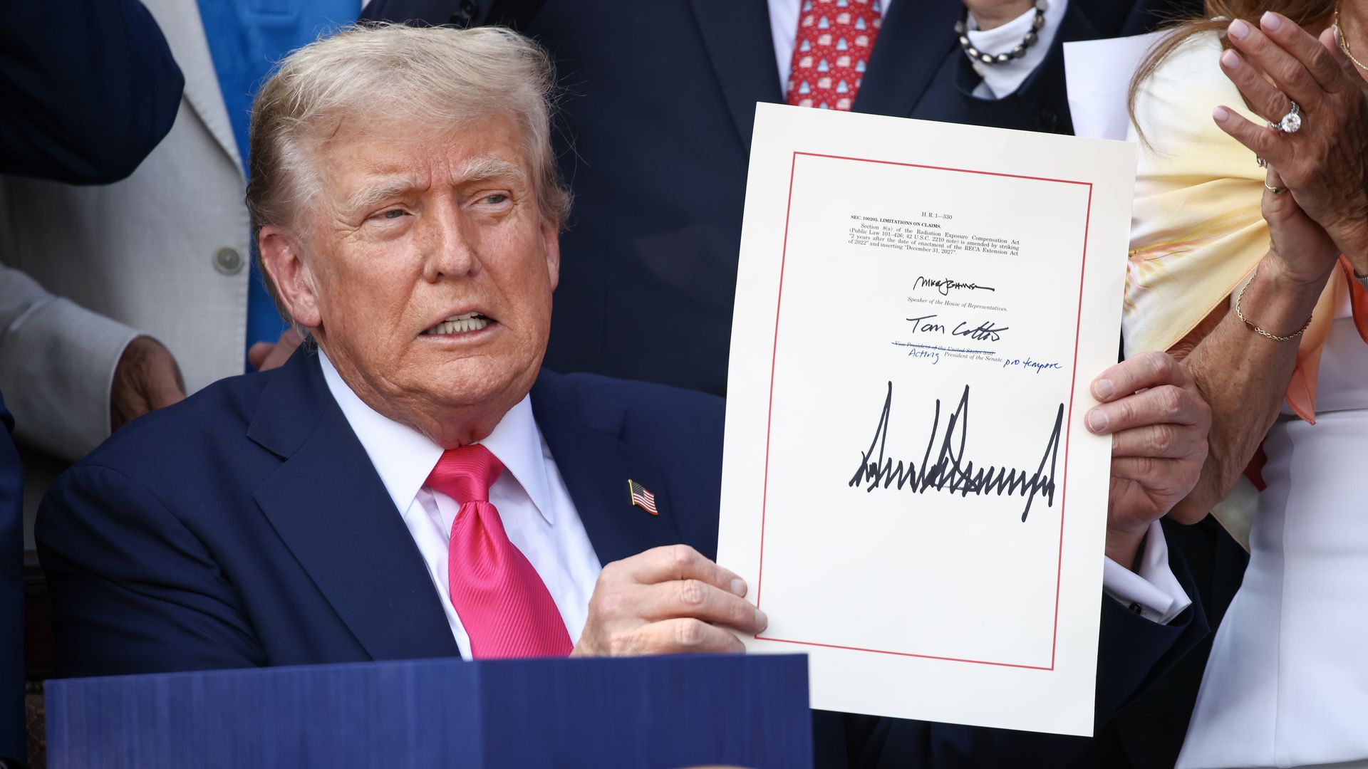 Donald Trump holding up a piece of paper with his signature