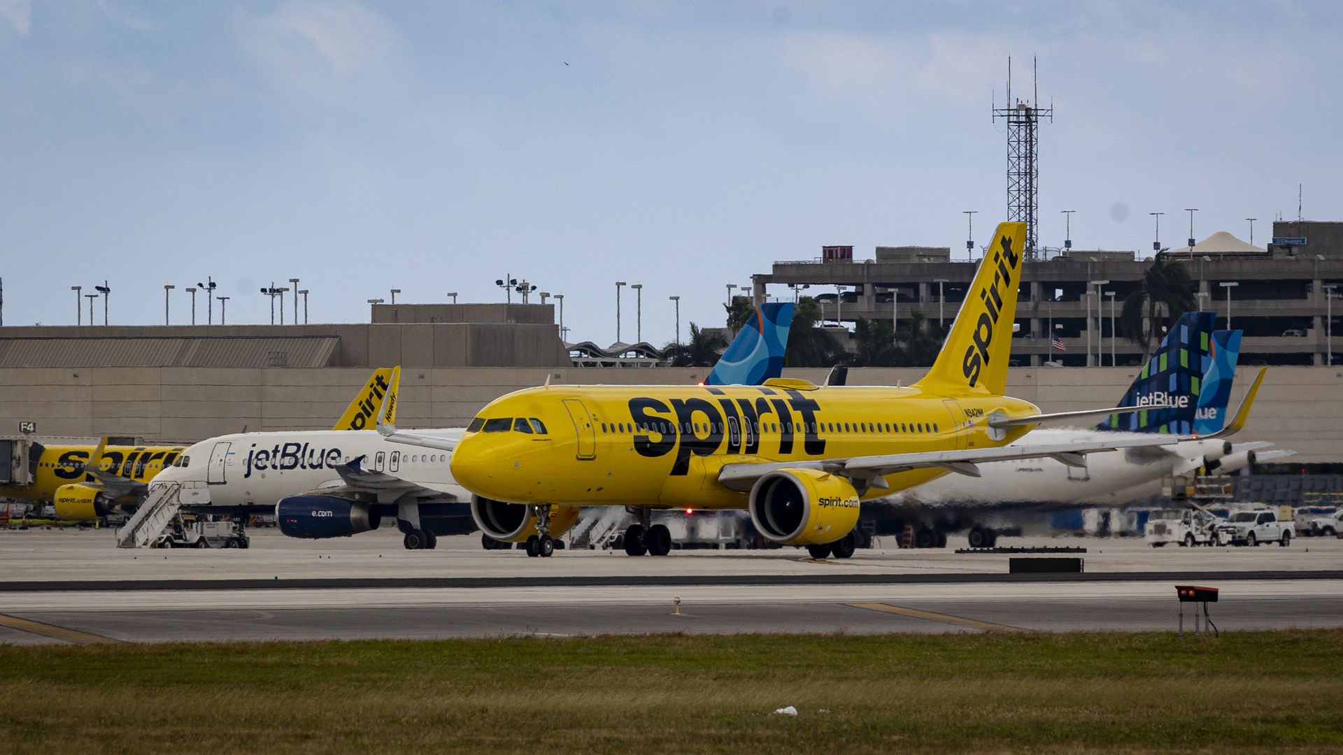 JetBlue and Spirit planes on an airport tarmac.