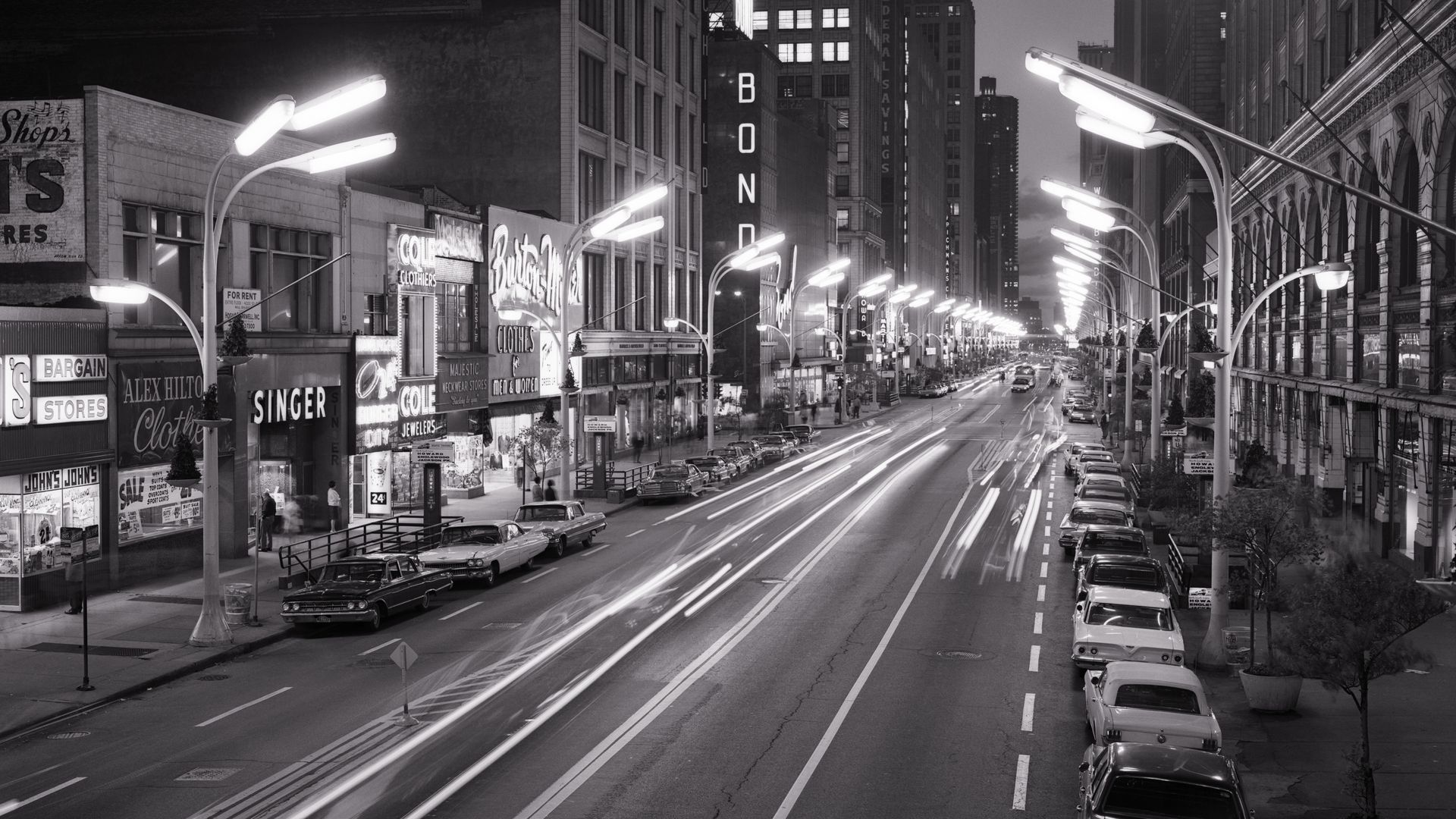 Photo of a street with several street lights and old signs, circa 1960s. 