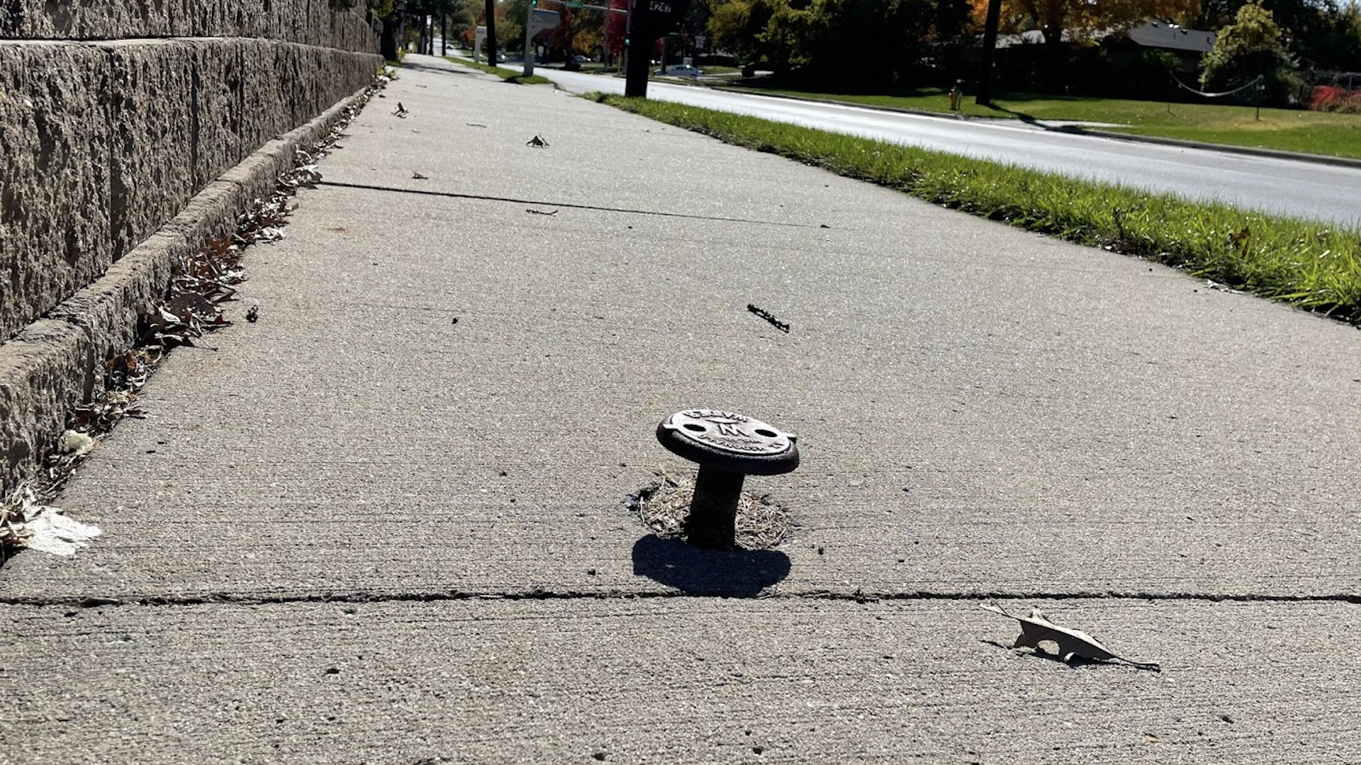 A valve protrudes from a sidewalk in Des Moines.