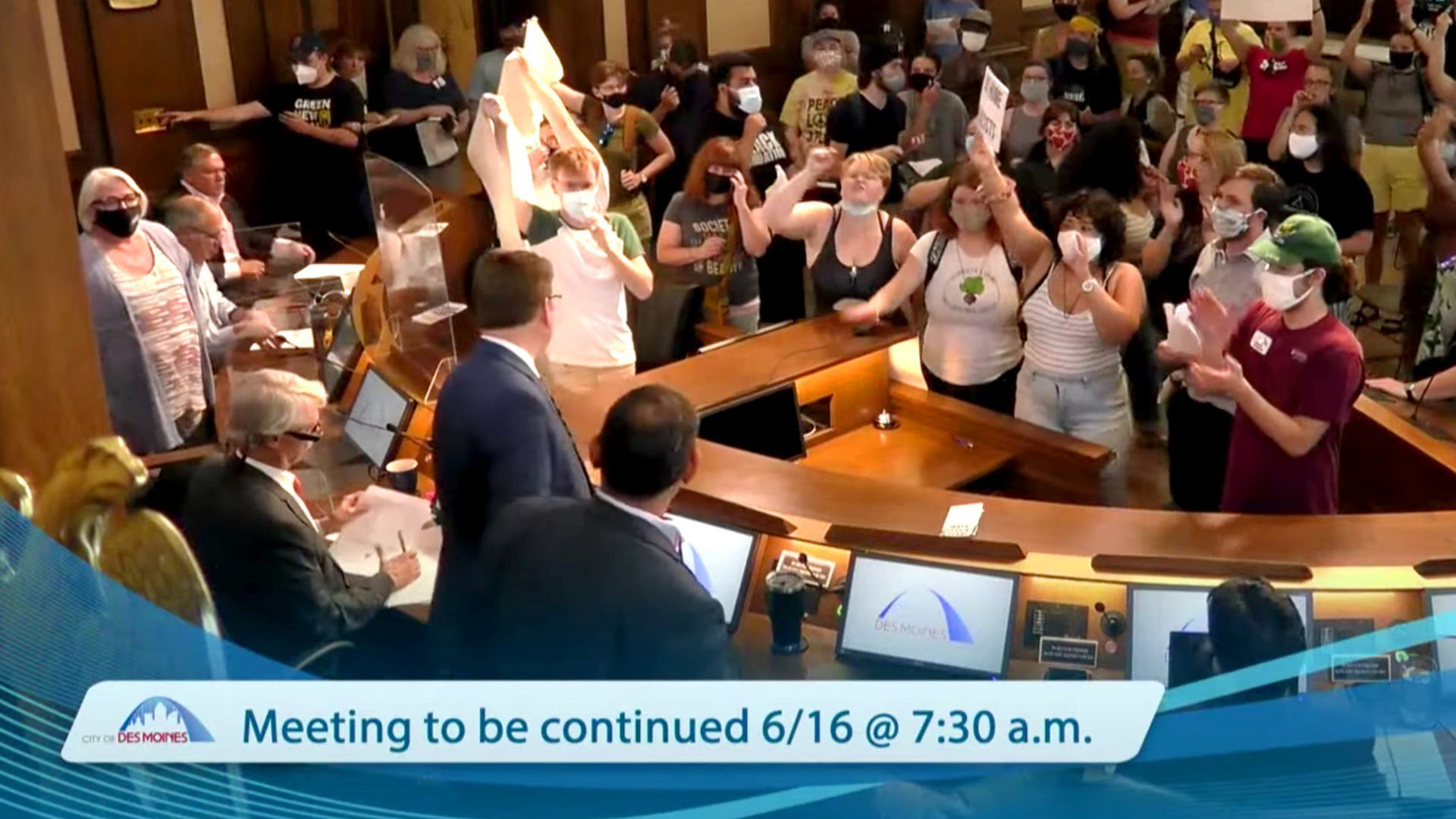 Protesters showed up at Des Moines' City Council meeting Monday with signs.