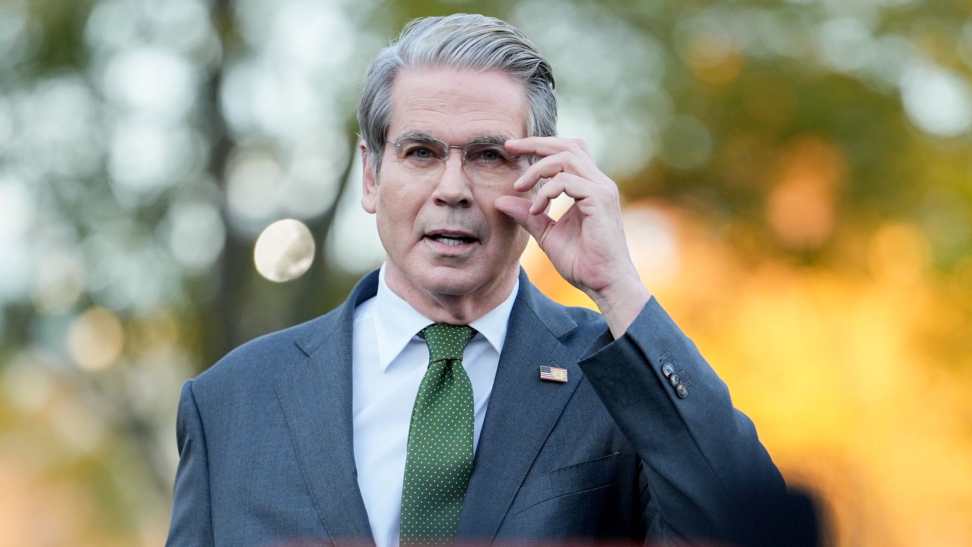 Treasury Secretary Scott Bessent, walking and adjusting his glasses. 