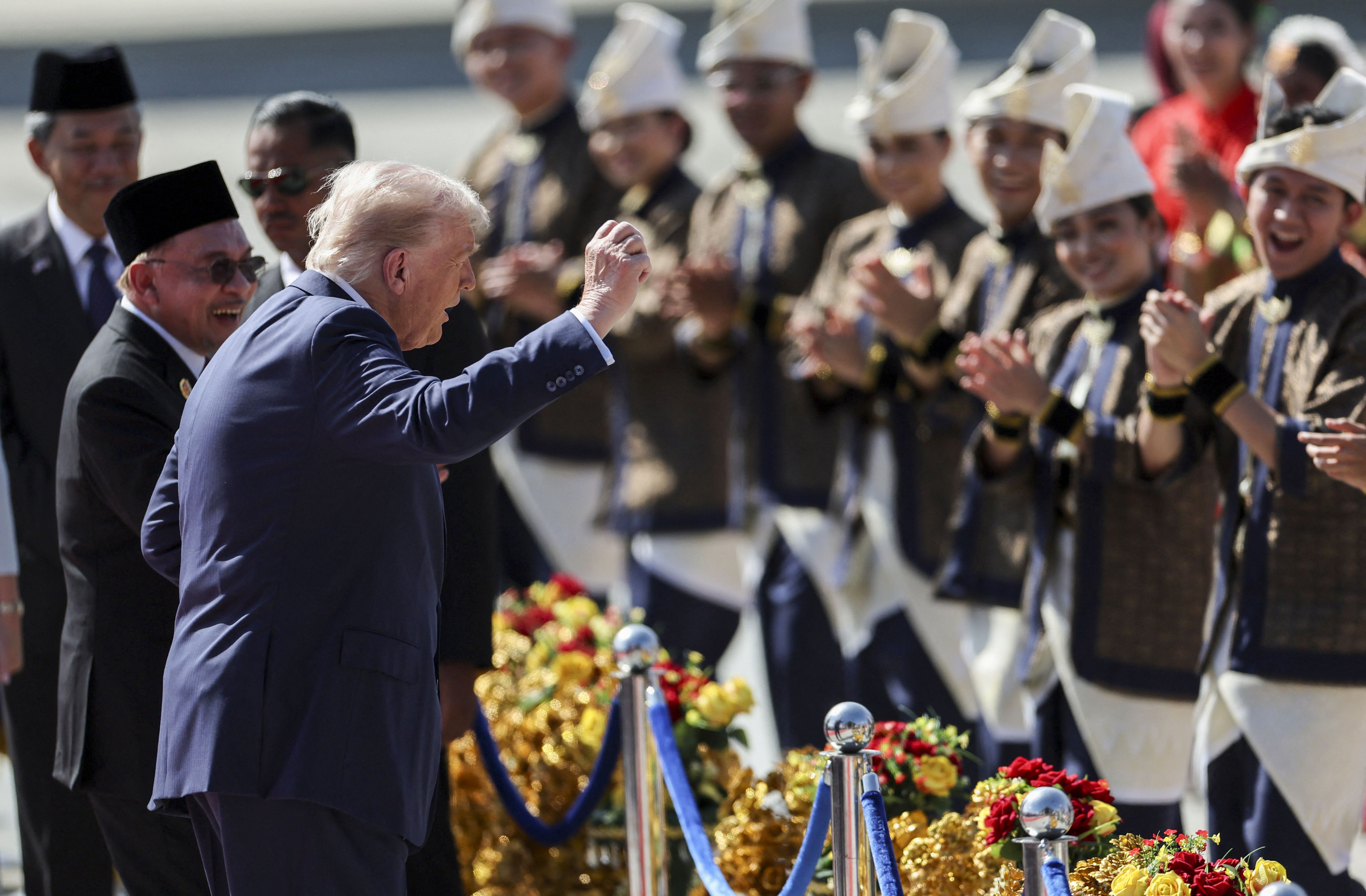 S President Donald Trump (C) joins performers for a dance during the welcome ceremony next to Malaysia's Prime Minister Anwar Ibrahim (L) as he arrives on Air Force One at Kuala Lumpur International Airport in Sepang on October 26, 2025. US President Donald Trump arrived in Malaysia on October 26 on
