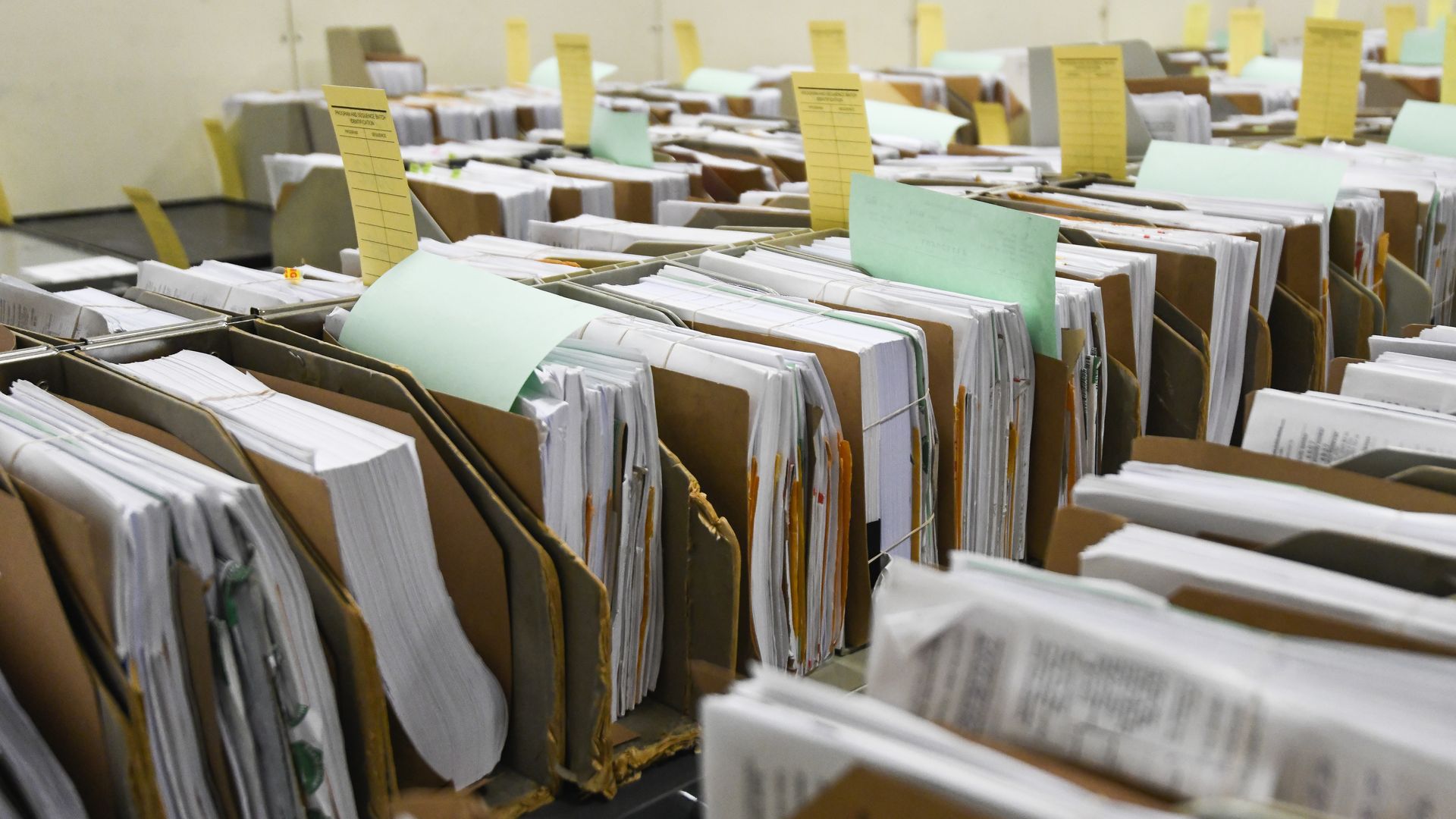Stacks of papers sit on a shelf.