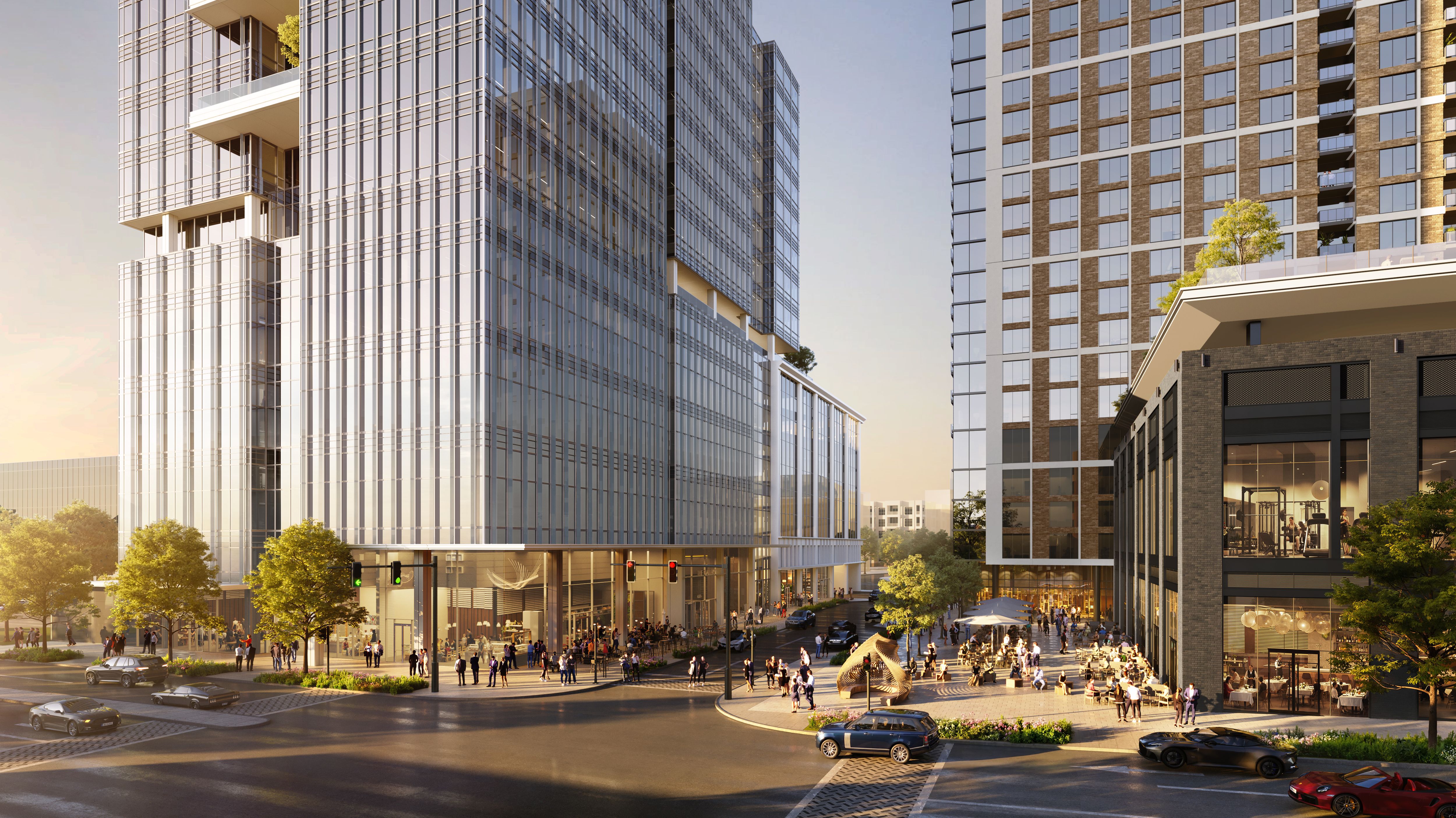 Wide city scene of glass-skyscraper towers framing a busy plaza with outdoor seating, pedestrians, trees, and cars at sunset.