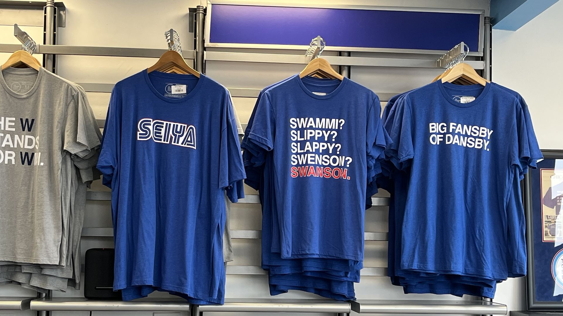 A gray t-shirt and three blue ones each with text.