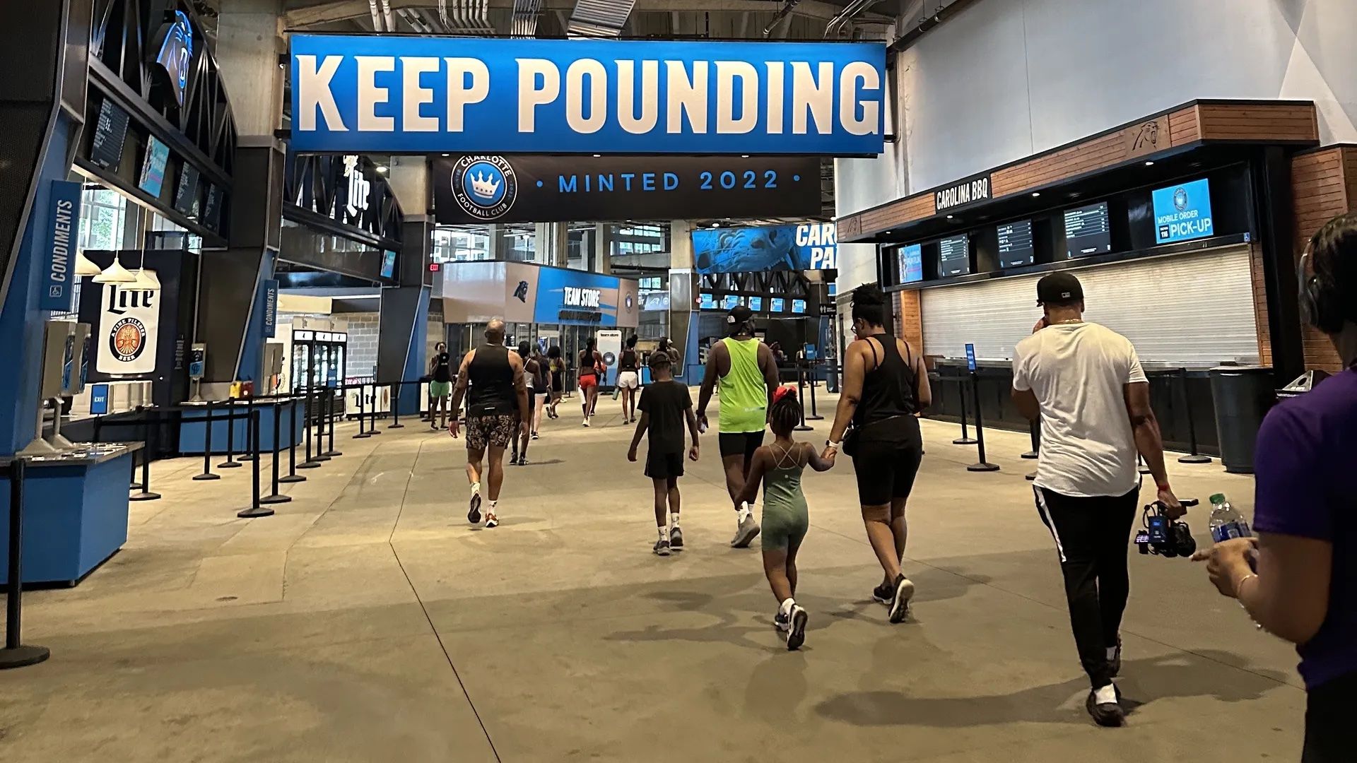 people running under the keep pounding sign inside the Bank of America stadium