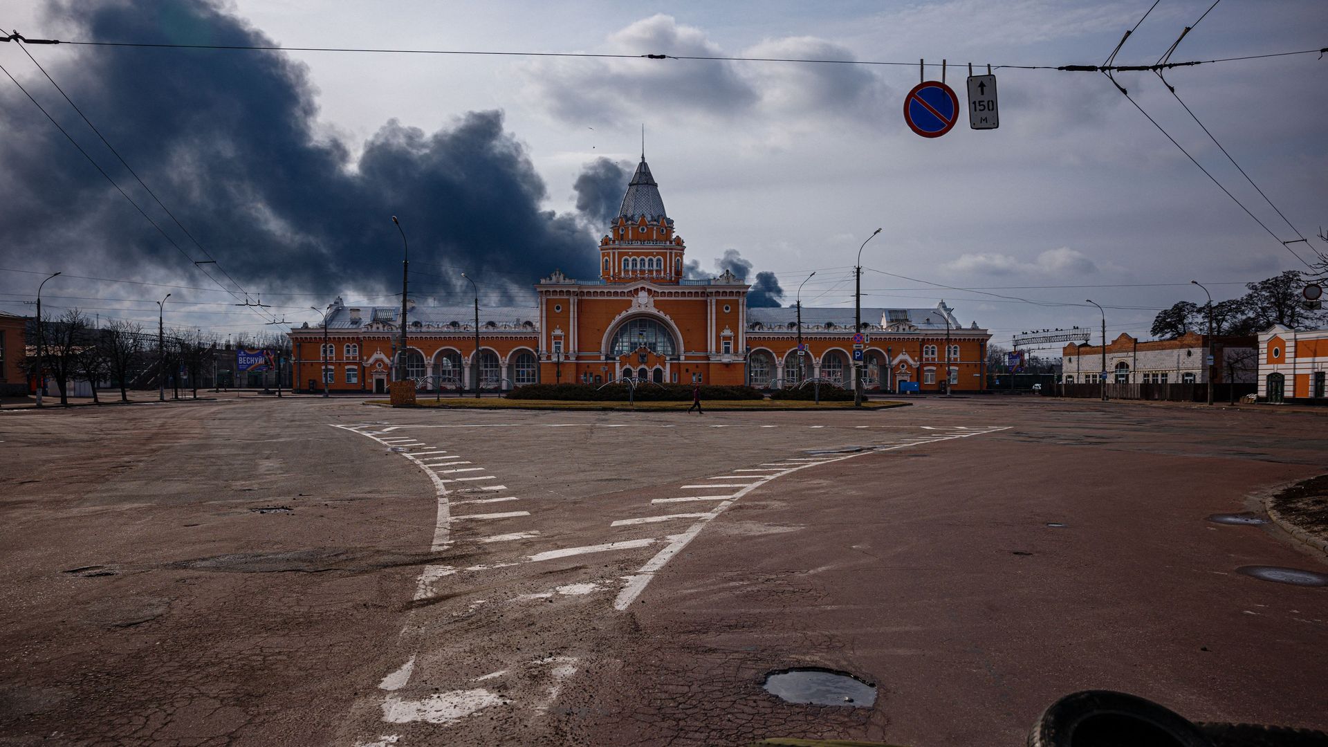 Photo of smoke rising on the horizon behind a train station