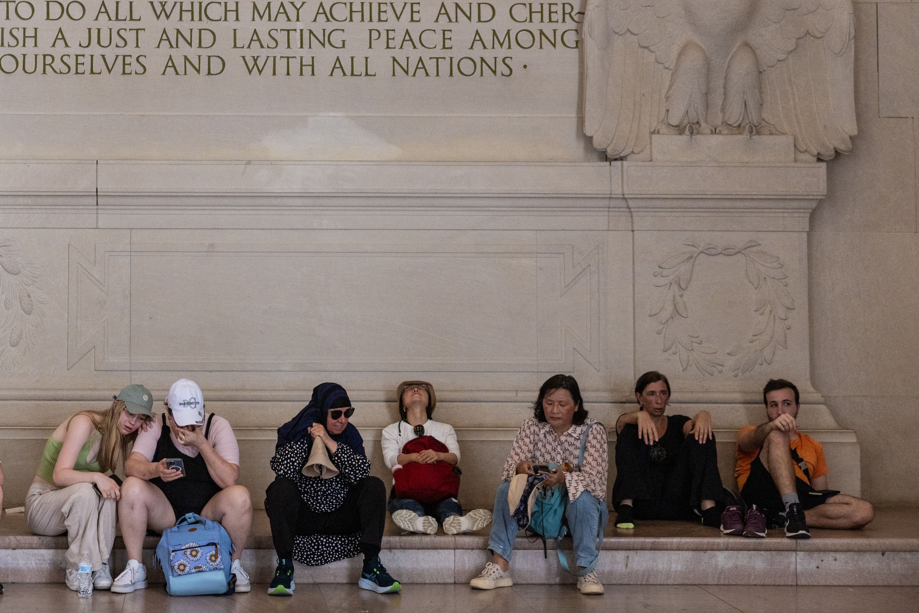 People sittting down and visibly exhausted in the Lincoln Memorial.