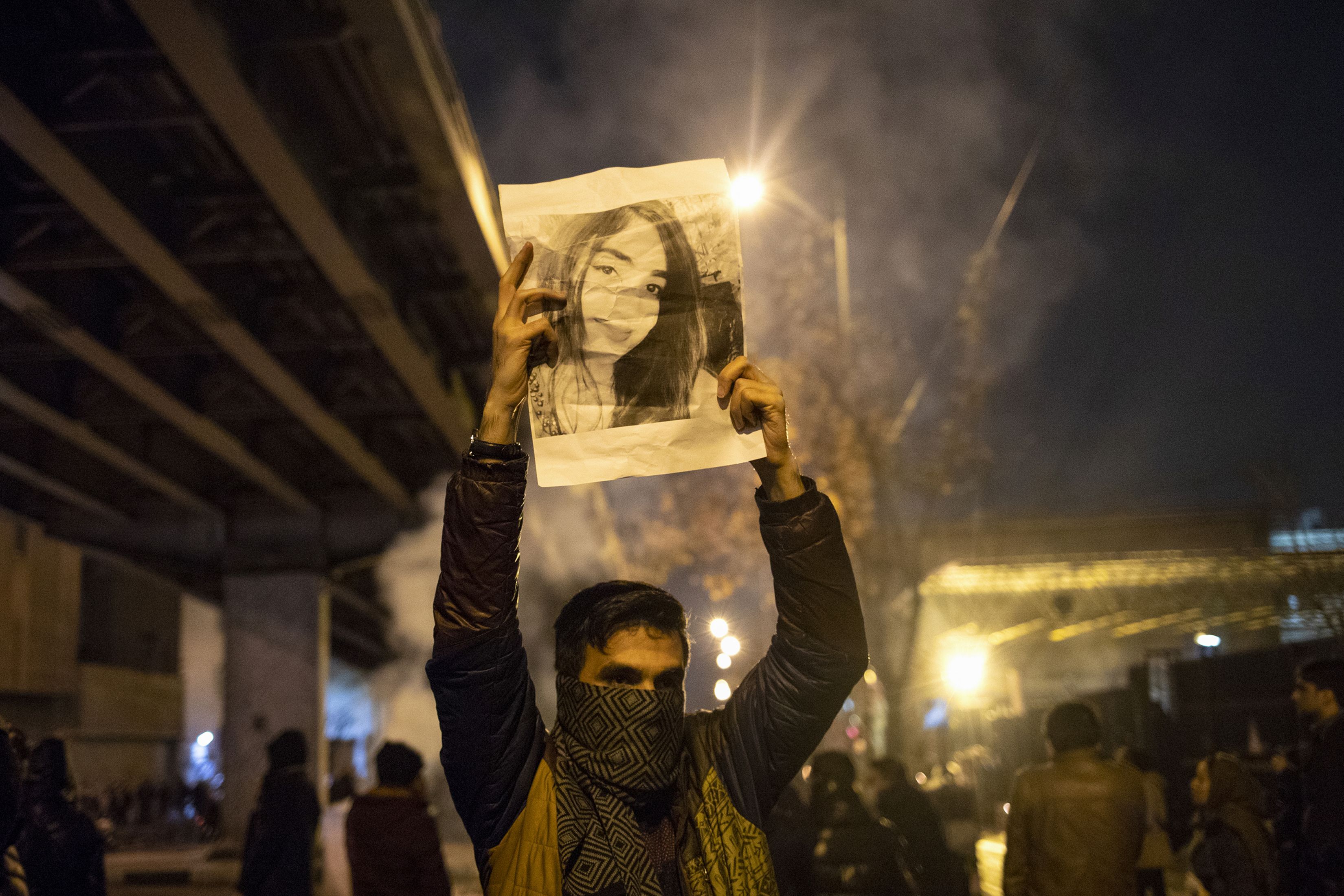  An Iranian man holds a picture of a victim of the Ukrainian Boeing 737-800 plane crash during a demonstration in front of Tehran's Amir Kabir University