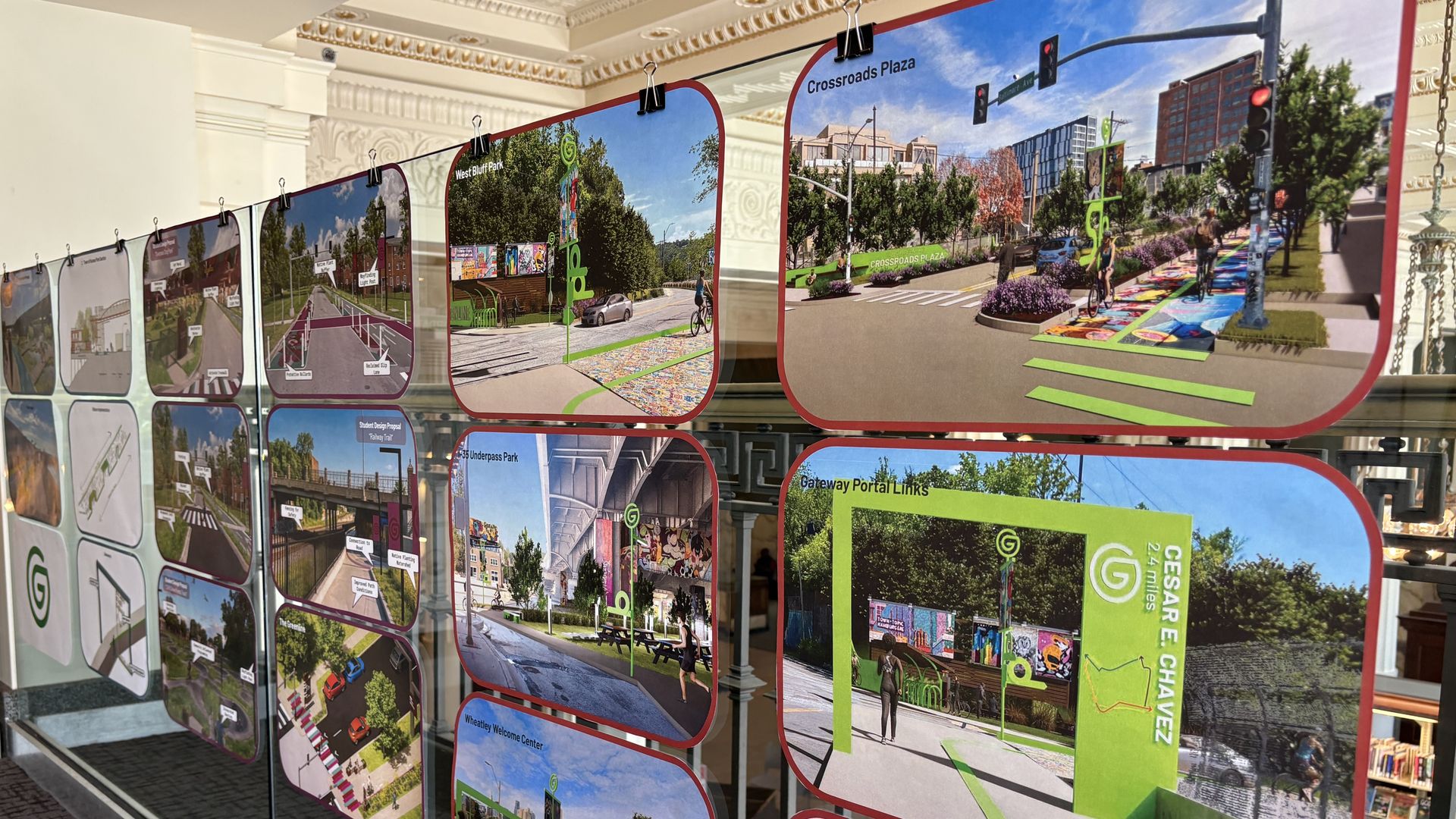 Interior showroom with curved panels showing renderings for "Crossroads Plaza": bike lanes, vibrant crosswalks, trees, pedestrians, and cars along a city boulevard.