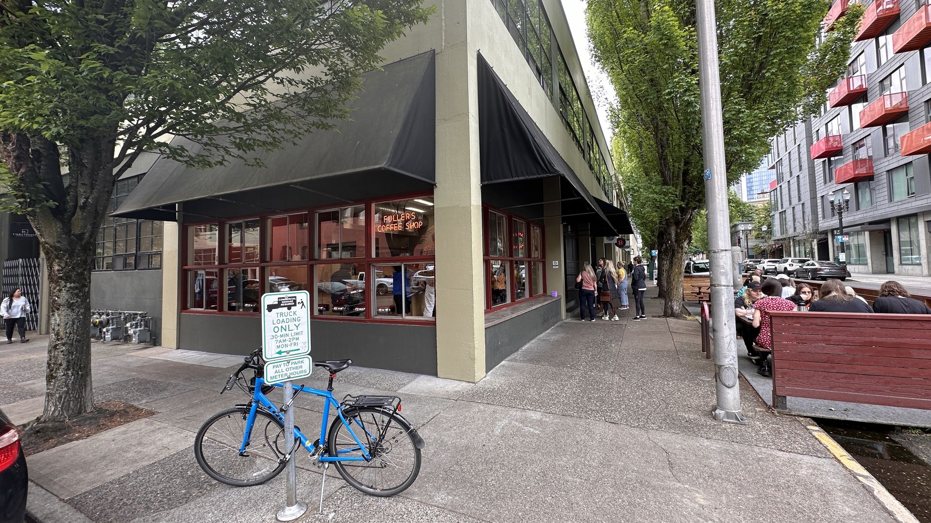 Corner coffee shop with outdoor seating and a blue bike