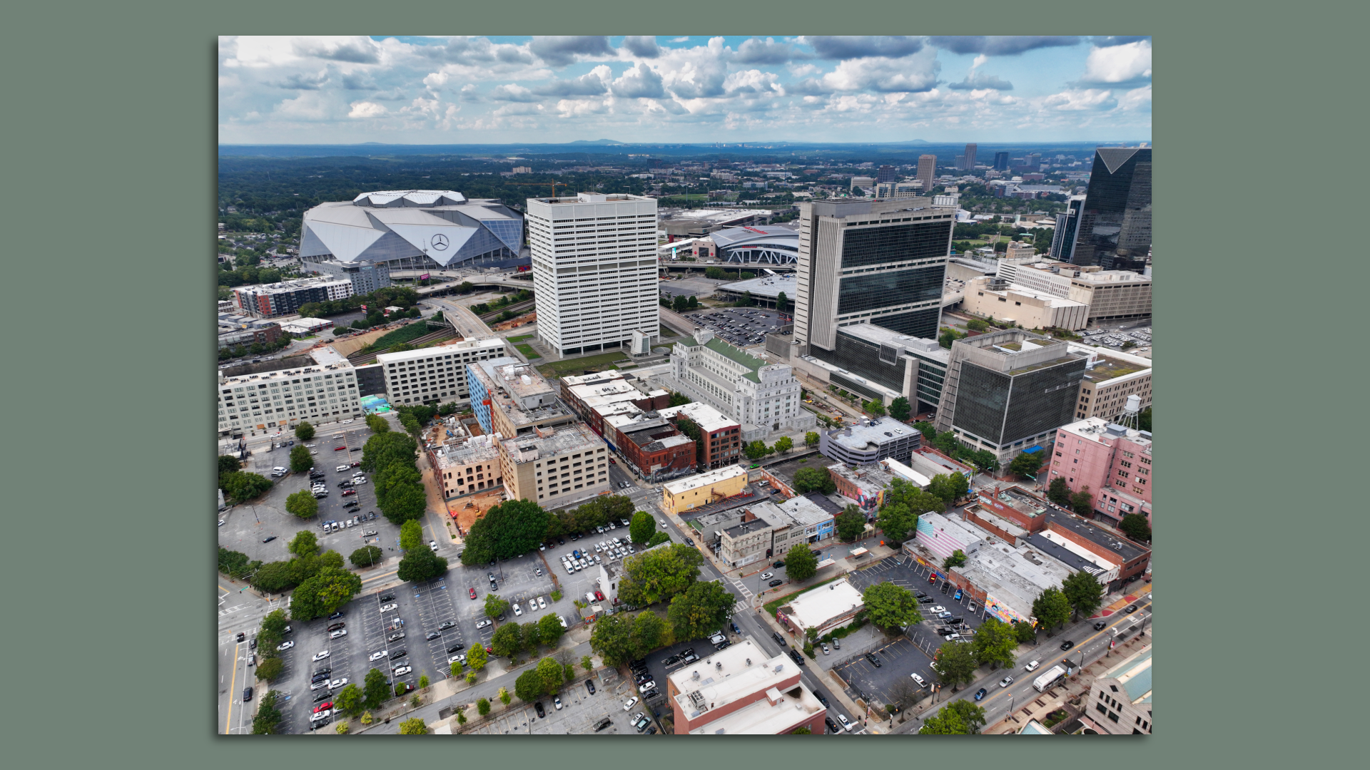 An aerial photo of a downtown area with a street grid and trees and a large stadium in the background