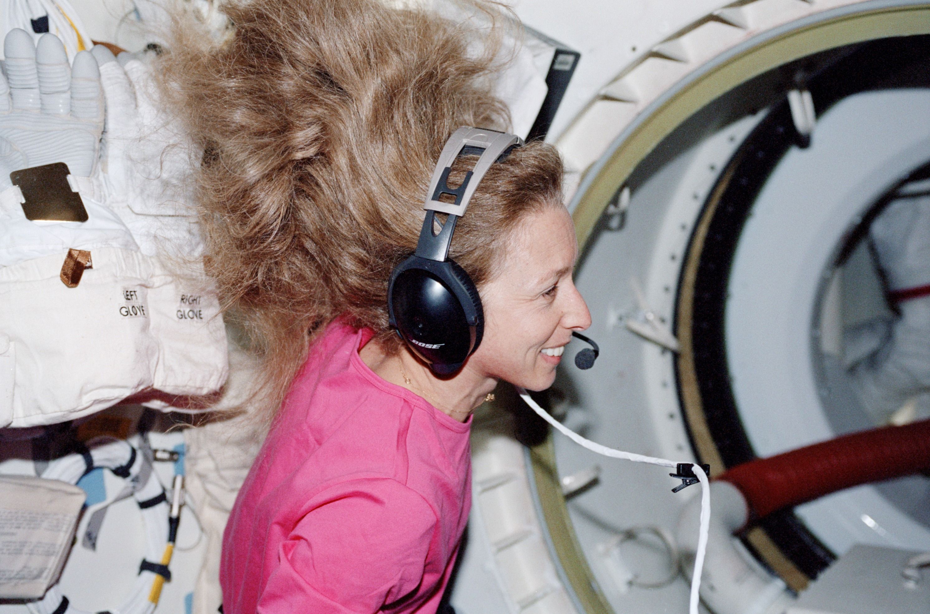 Photo of female astronaut in space with black headphones. 
