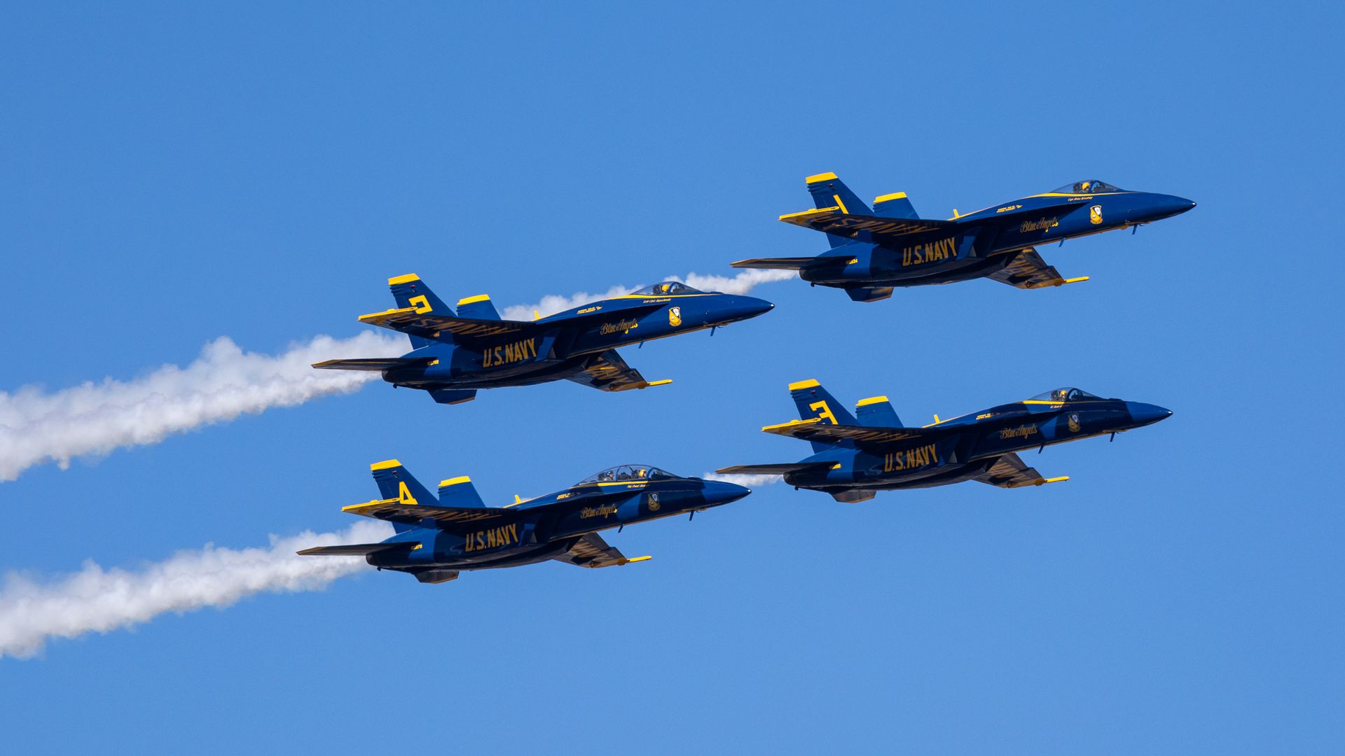 U.S. Navy Blue Angels jets fly across the sky with contrails