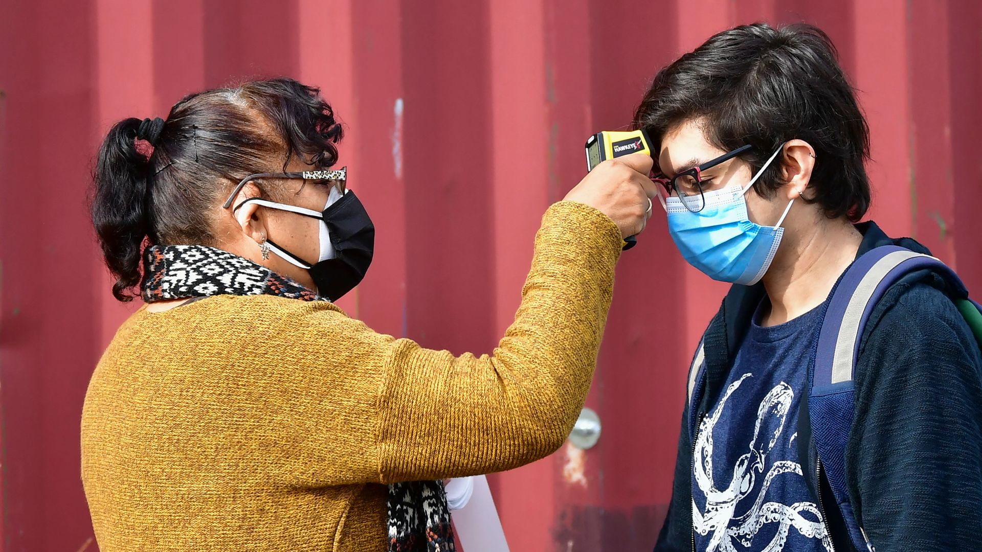 Someone gets a temperature check while wearing a blue face mask