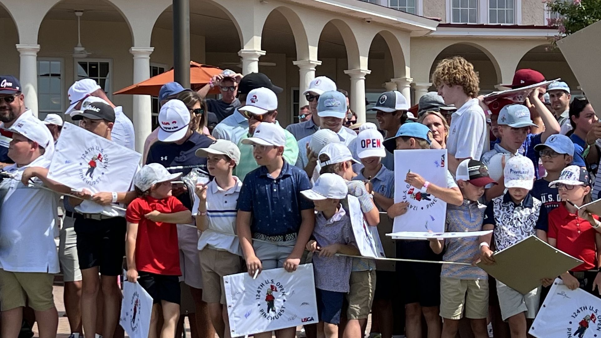 kids in golf clothes at the US Open at Pinehurst hold memorabilia waiting for golfers to sign