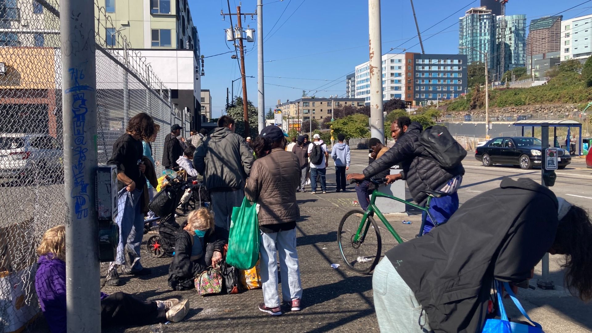 A group of people hang out outside a razor-wire fence in a Seattle neighborhood. 
