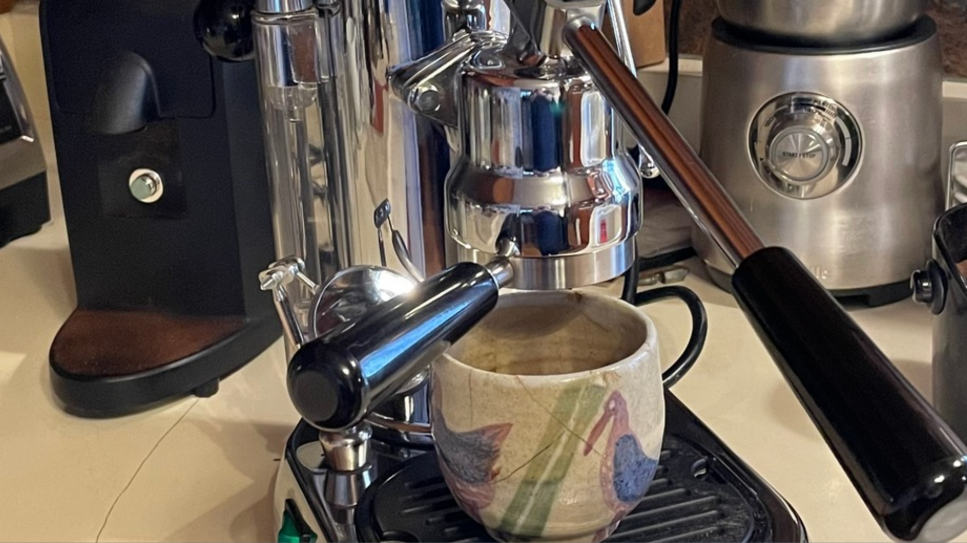A coffee grinder, manual lever espresso machine and a milk frother. 