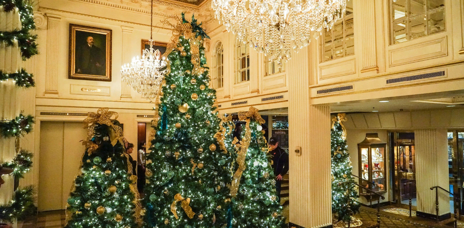 Image shows trees and white lights in a lobby with a chandelier.