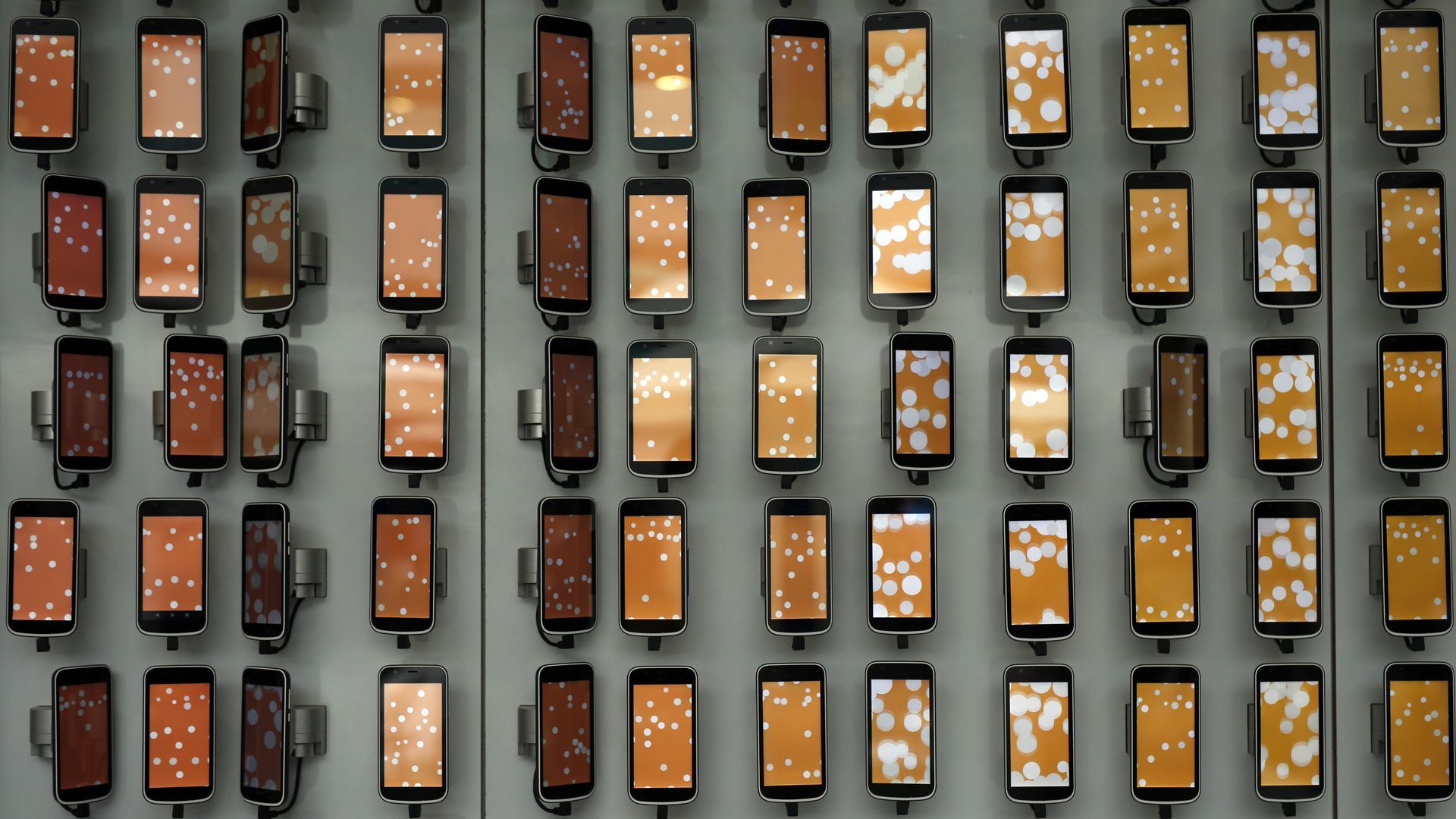 An array of cell phones mounted on a wall 