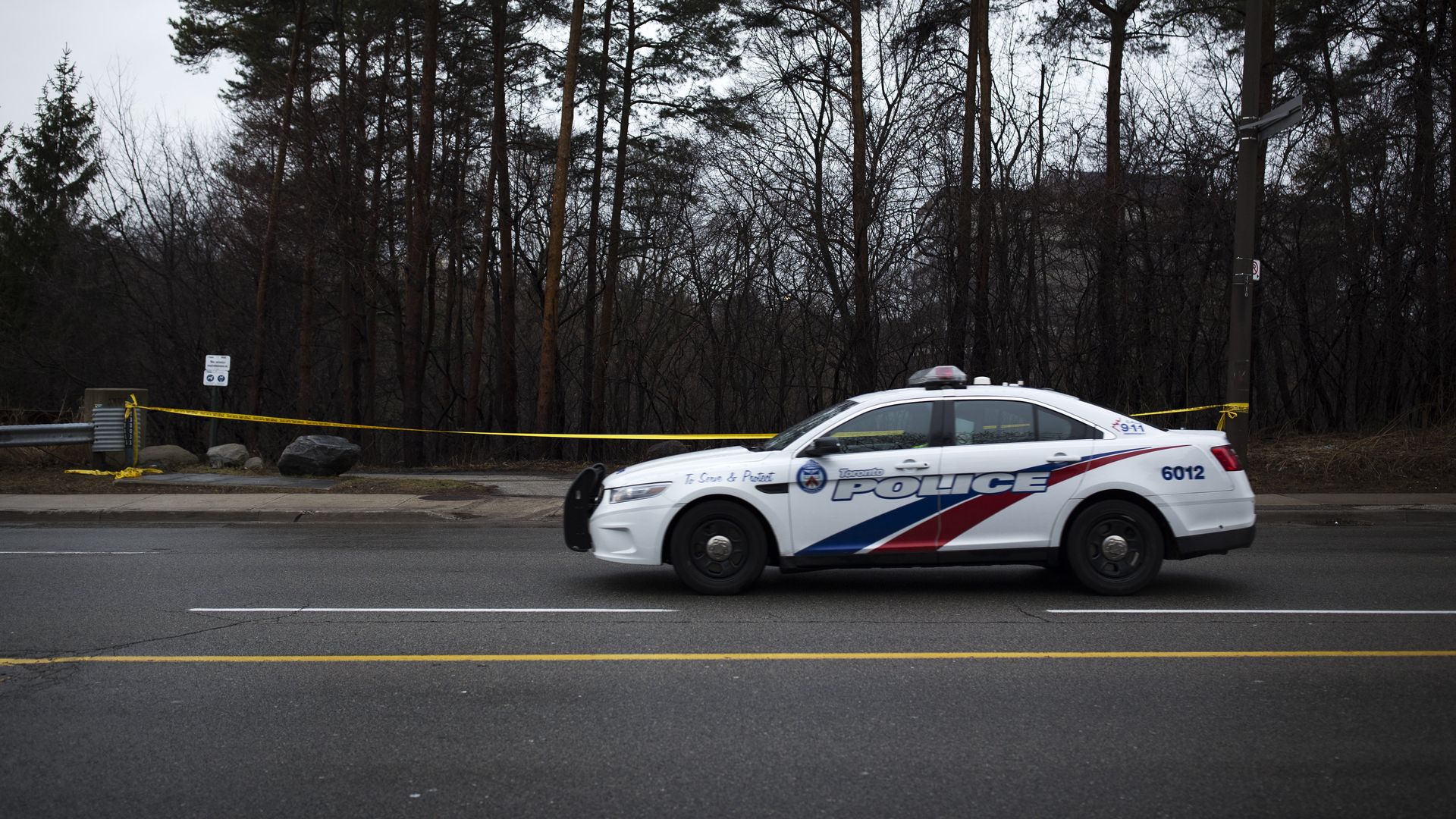 Photo of a police car parked next to an area roped off with police tape