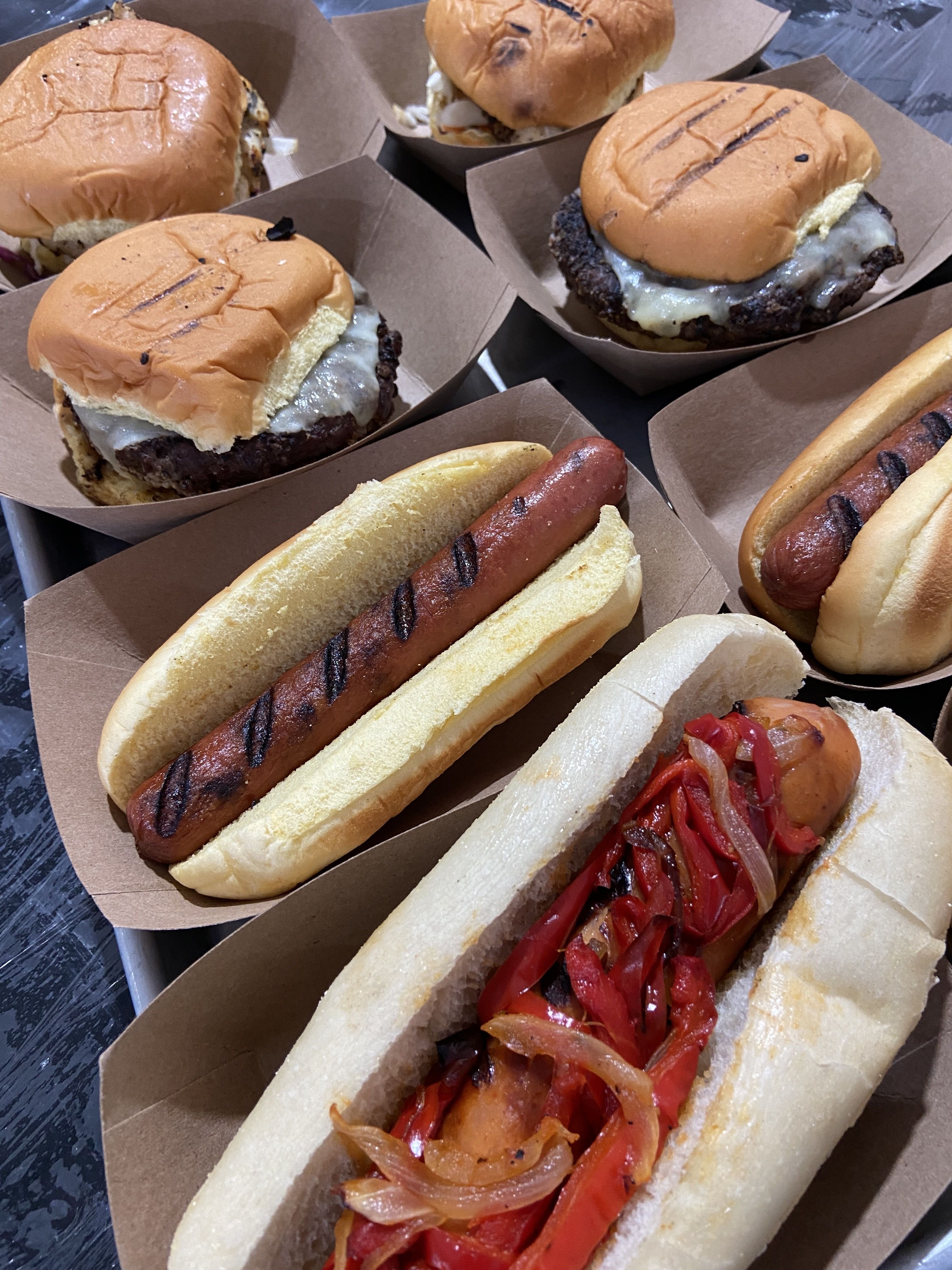 Burgers, hot dogs, grilled chicken sandwiches on a table.