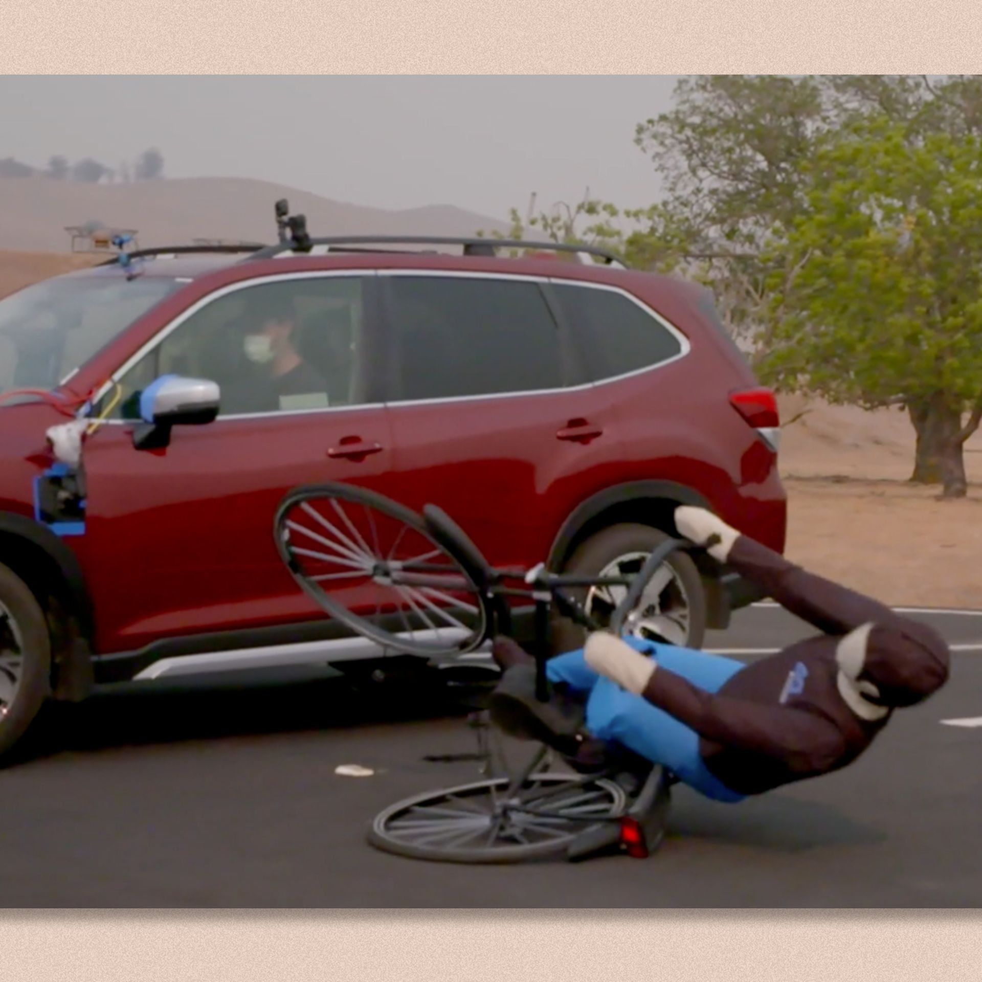 Screenshot from a crash video showing a dummy cyclist being hit by a car