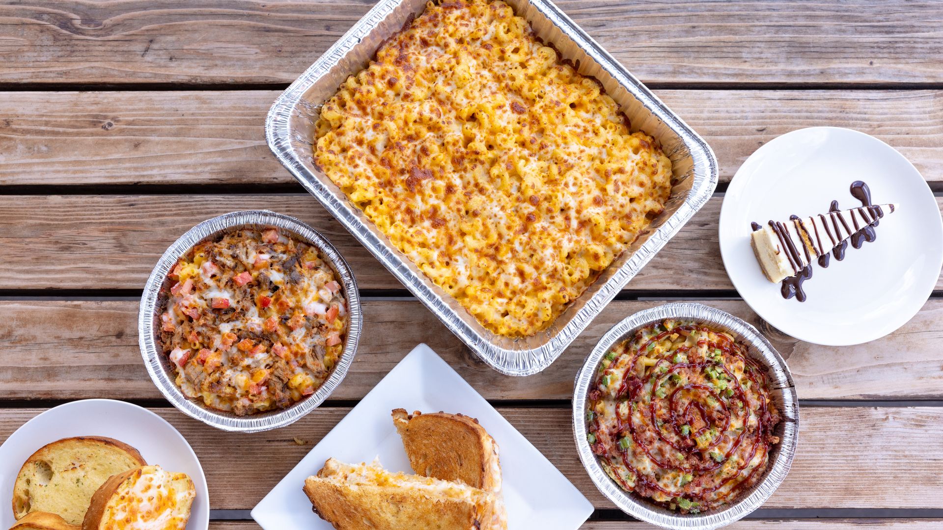 A table with bowls of macaroni and cheese and plates with grilled cheese.