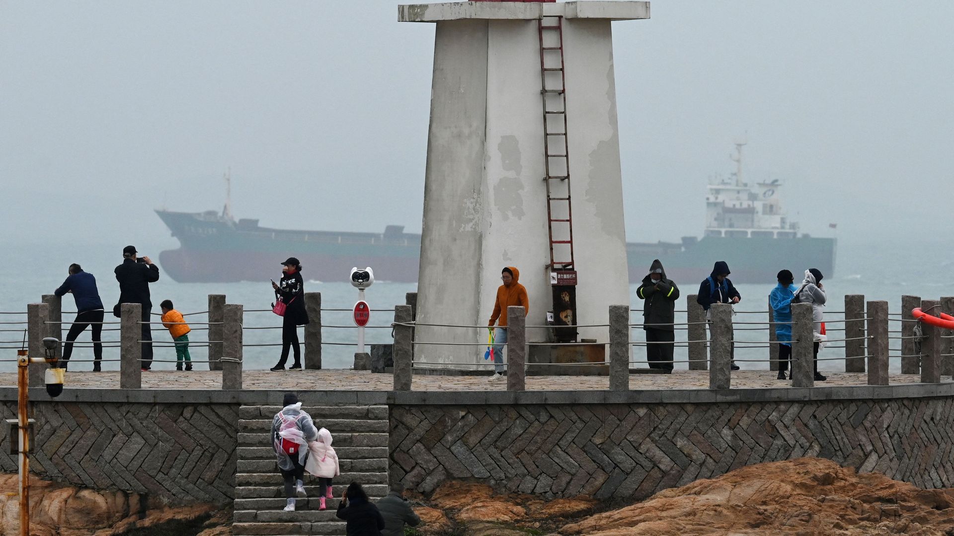 A cargo sails in the Taiwan Strait, behind tourists on a lighthouse on Pingtan island, the closest point to Taiwan, in China's southeast Fujian province on April 6.