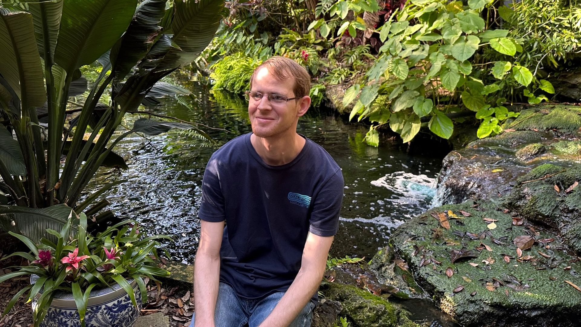 a man sits by a pond in a garden