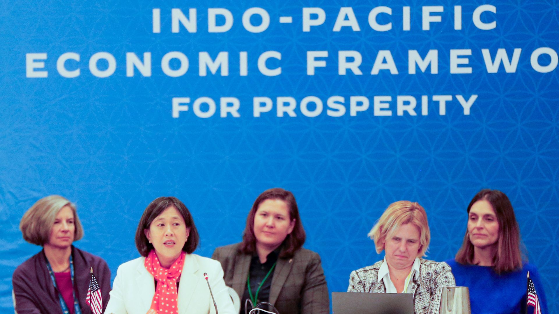 U.S. Trade Representative is shown speaking behind a microphone, joined by staff.