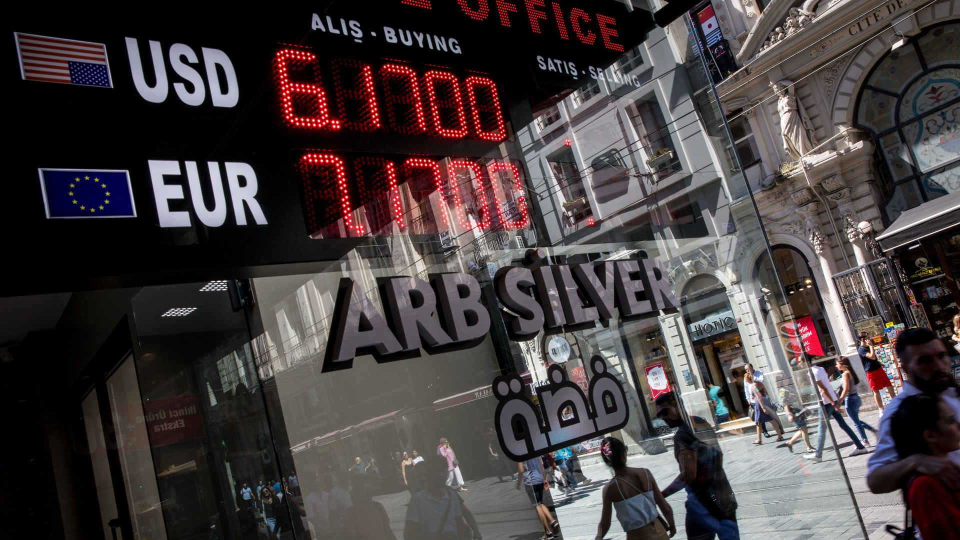 People walk in the street past a currency exchange office on August 13, 2018 in Istanbul, Turkey.