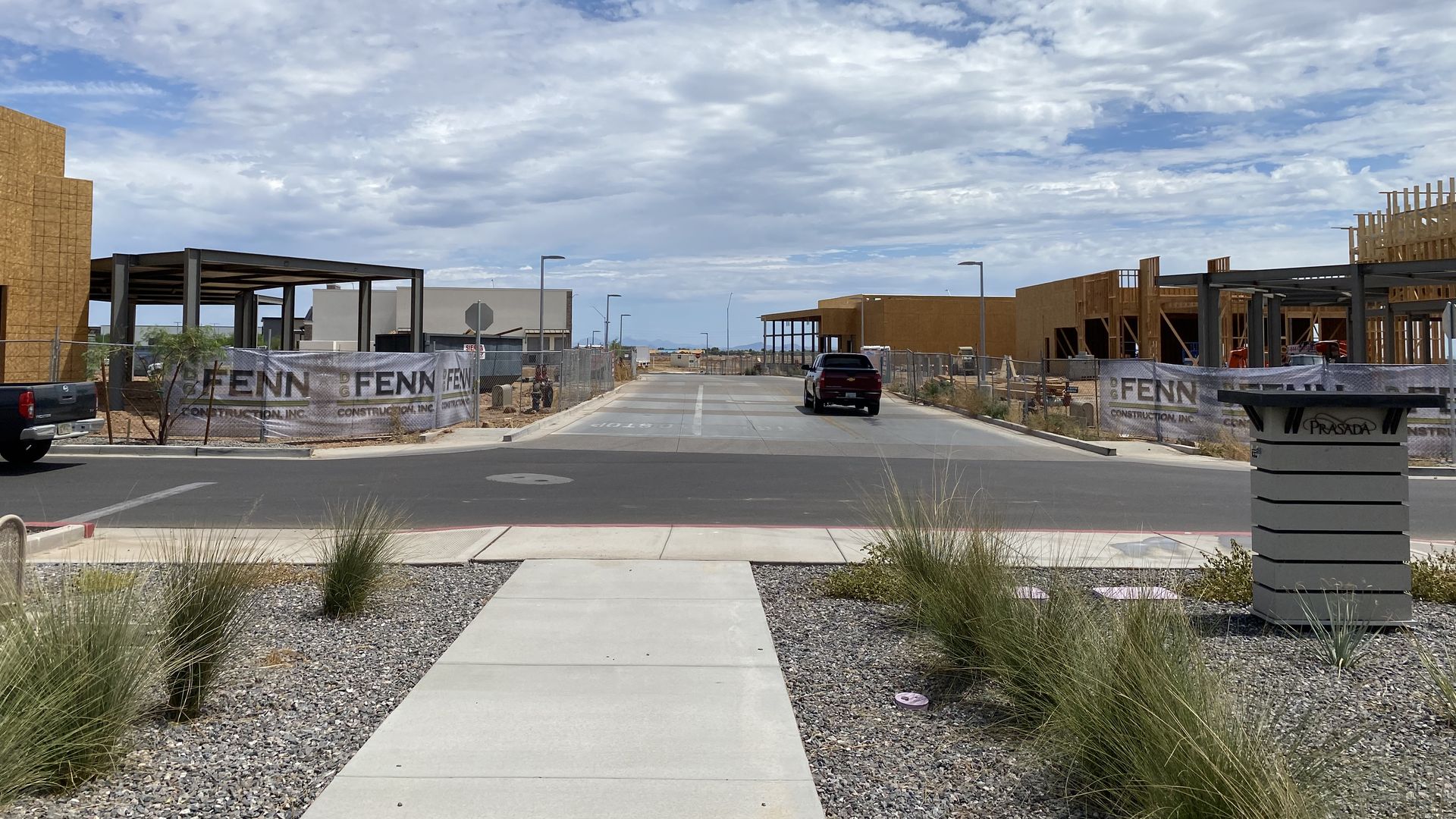 Several buildings under construction on both sides of a small road through a shopping center.