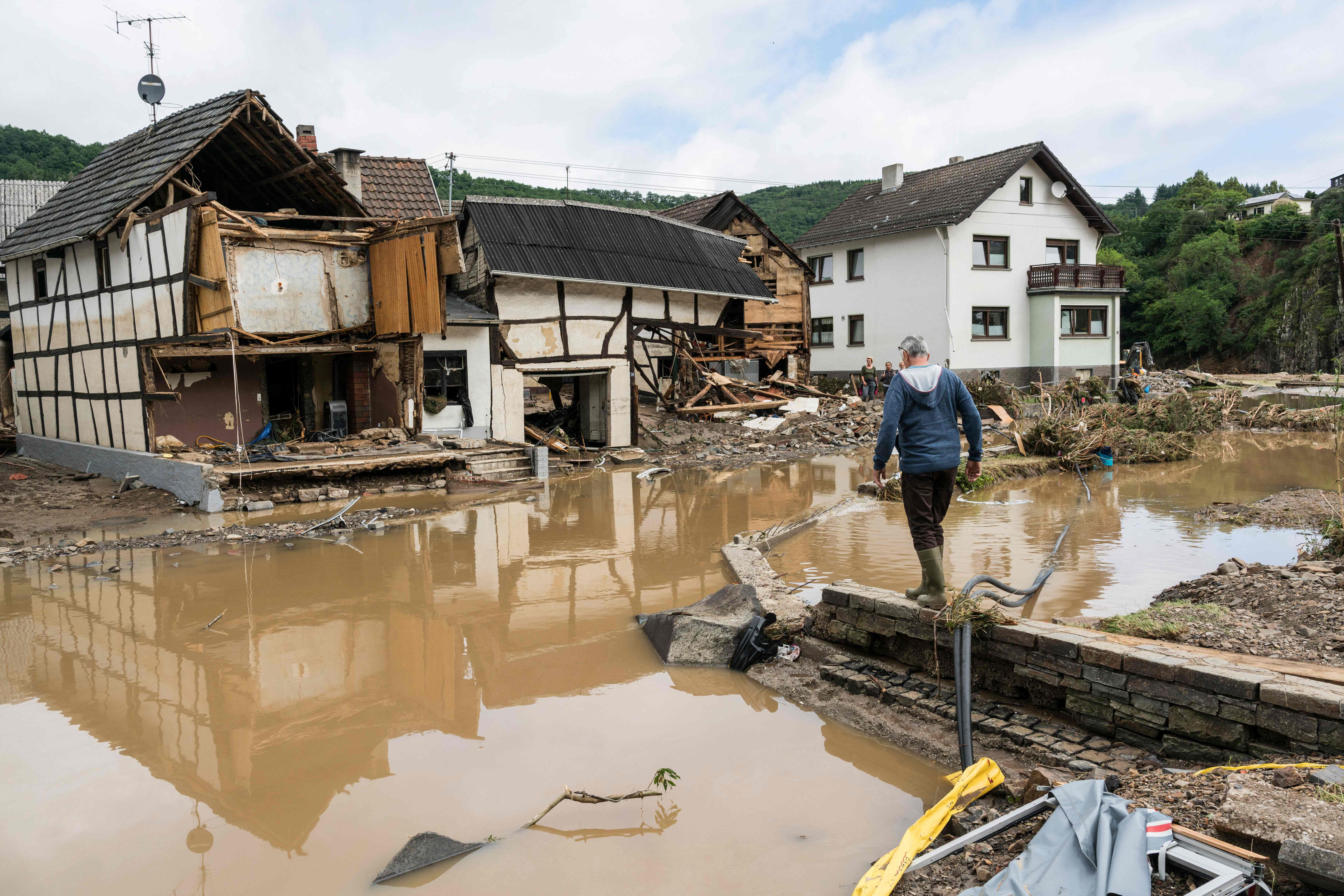 A man walks through the floods towards destroyed houses in Schuld near Bad Neuenahr, western Germany