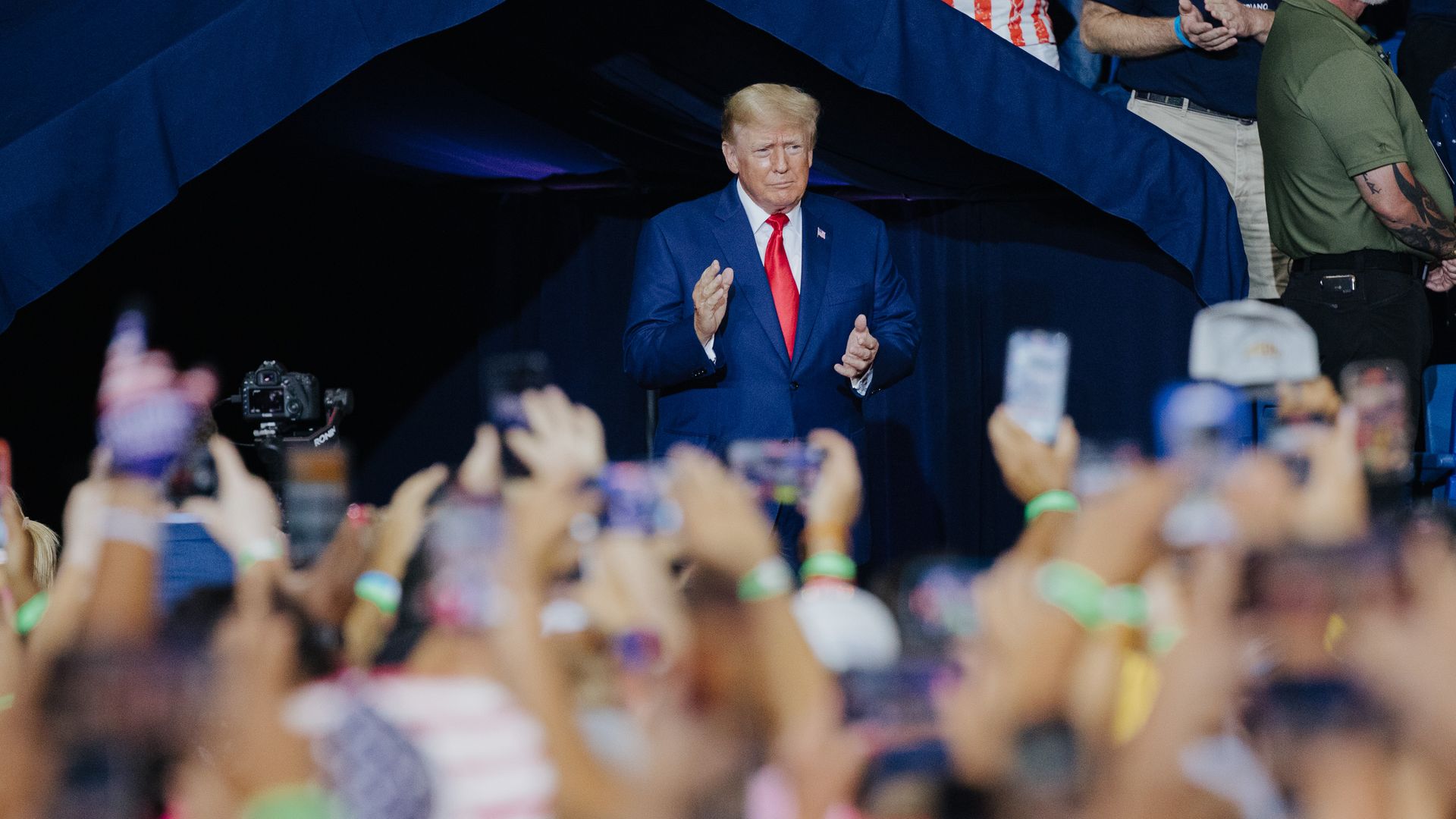 Photo of Donald Trump looking out at a crowd of people holding hands and phones at him