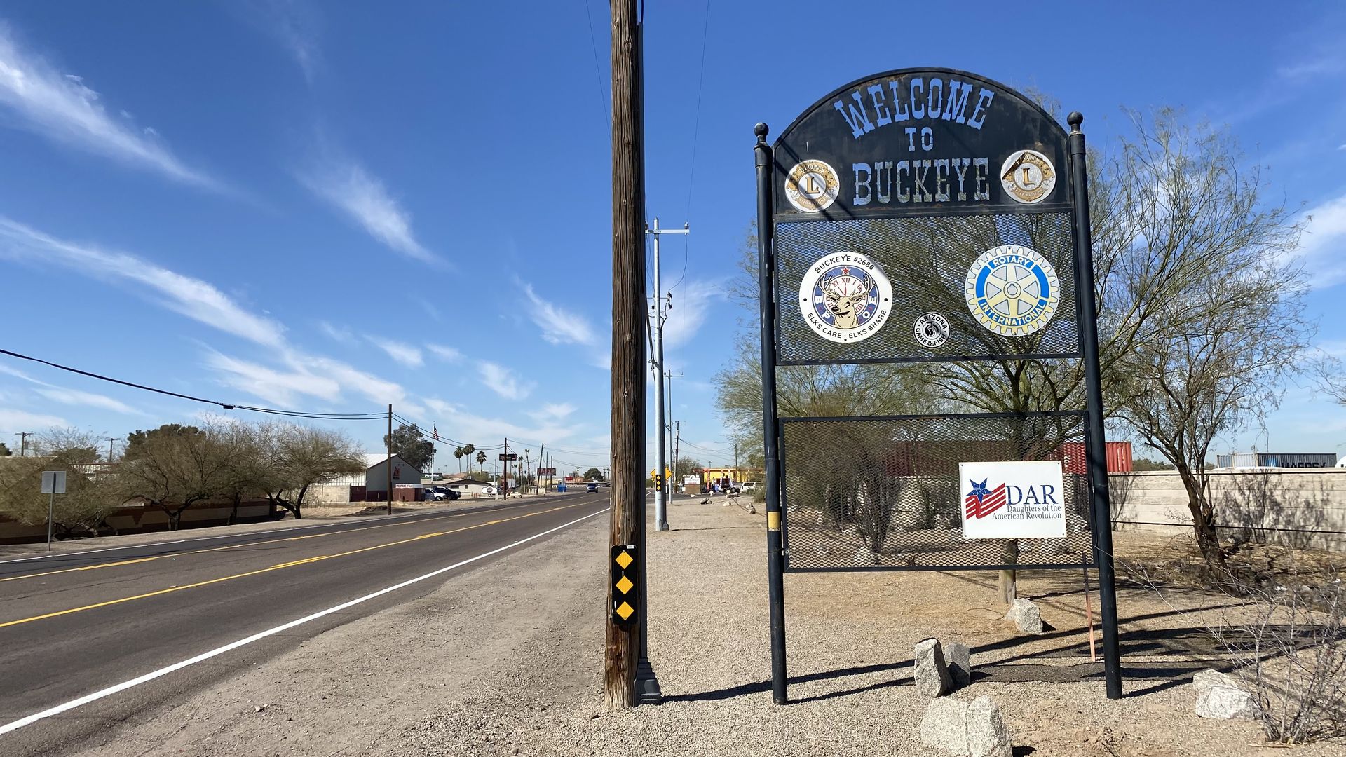 A metal sign that reads "Welcome to Buckeye" on the side of a road. 