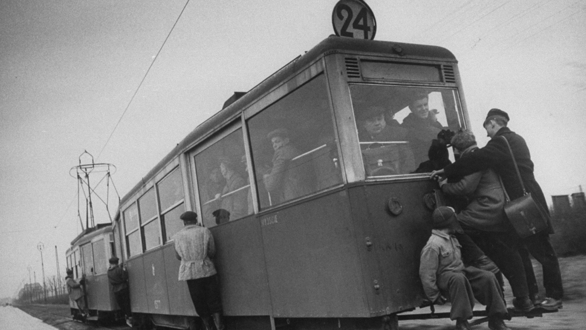 People hanging off a streetcar.