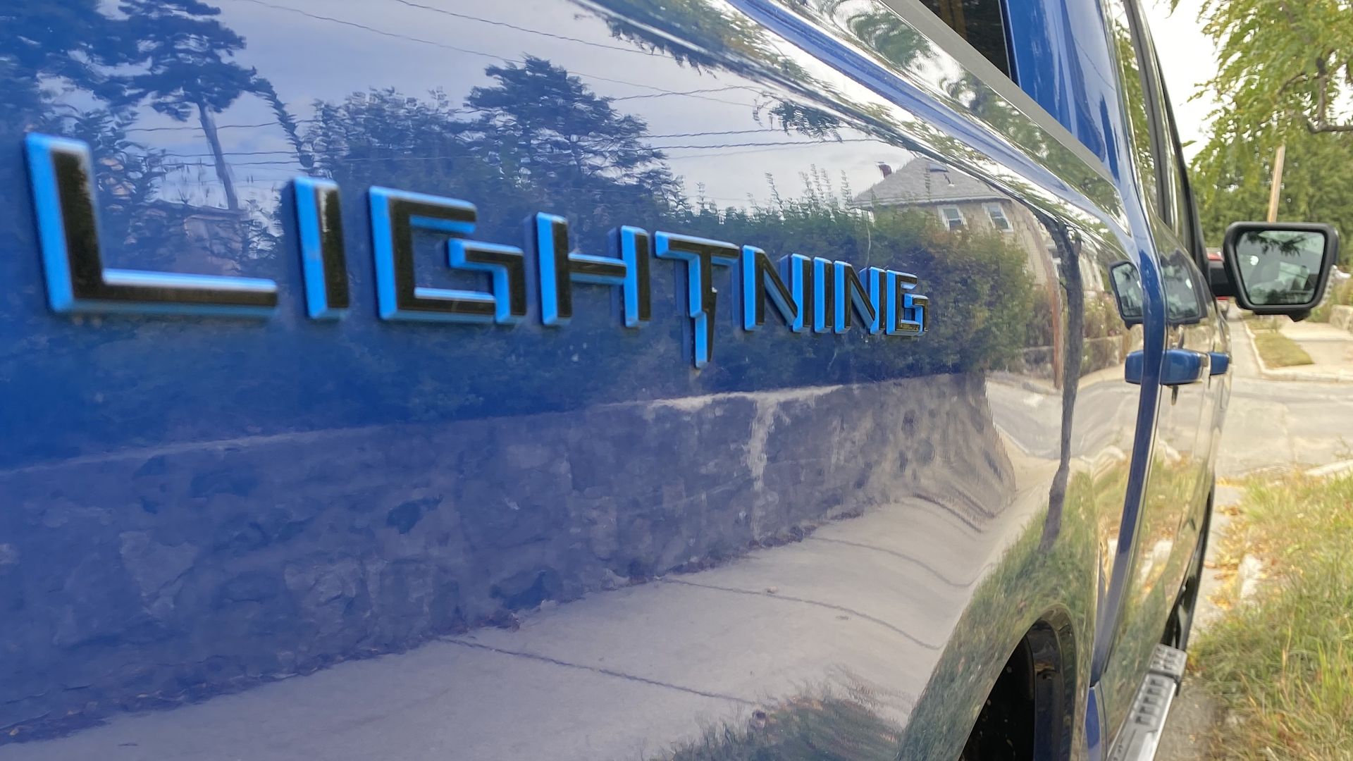 A close-up image of the "Lightning" logo on the side of a blue Ford F-150 pickup.