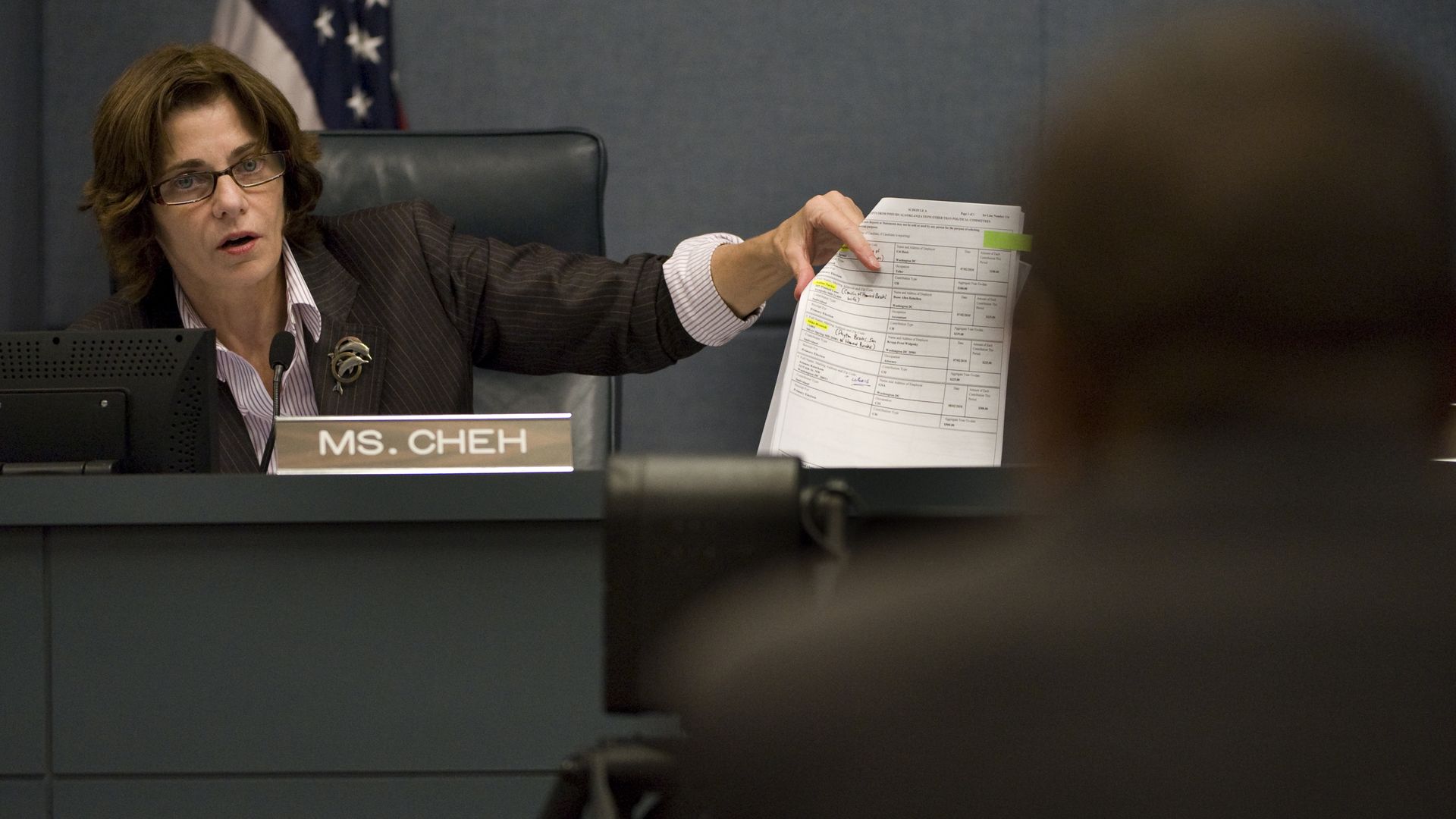 Mary Cheh on the council dais holds up a piece of paper while she leads an investigation