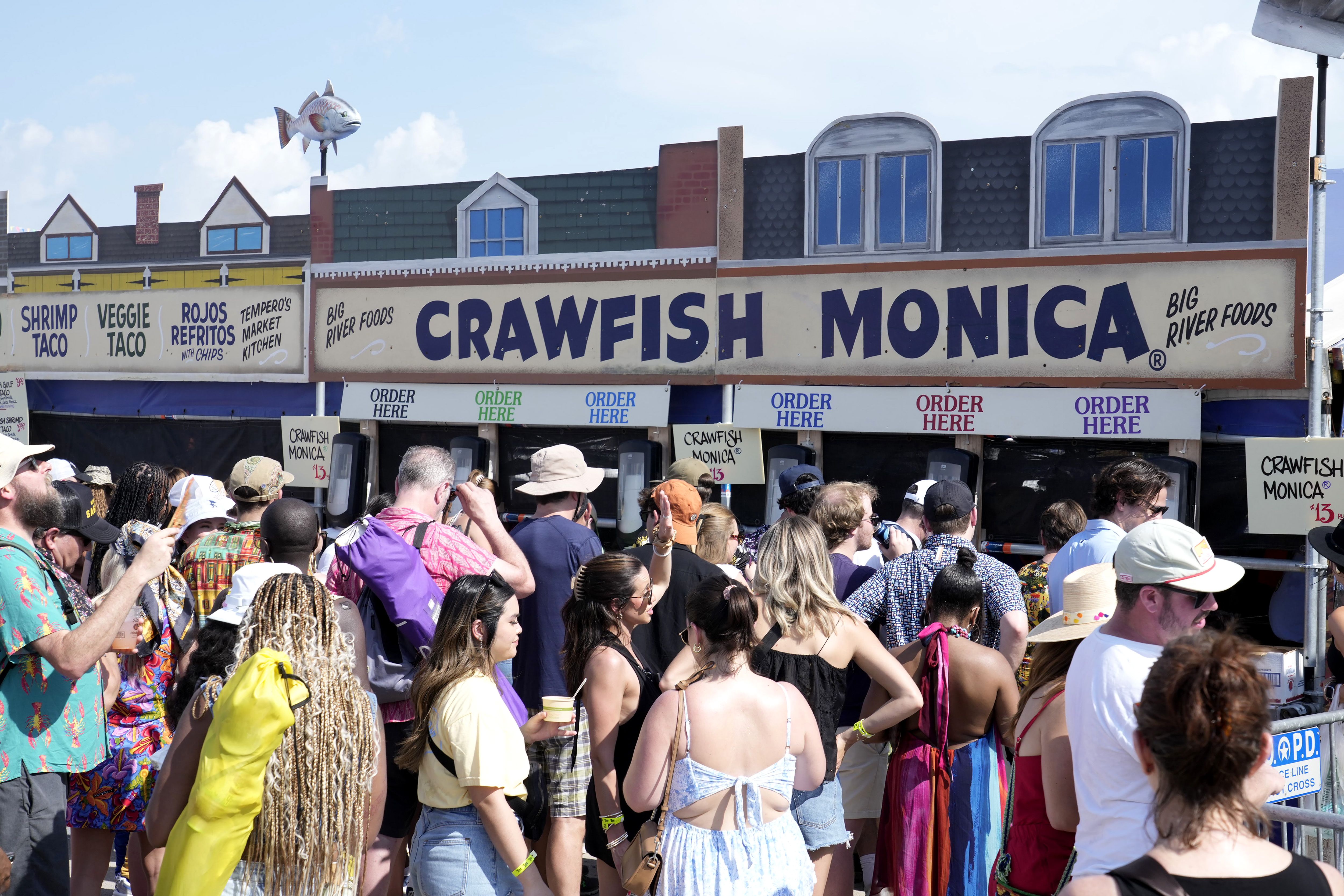 Image shows a food booth with "Crawfish Monica" written on the sign.