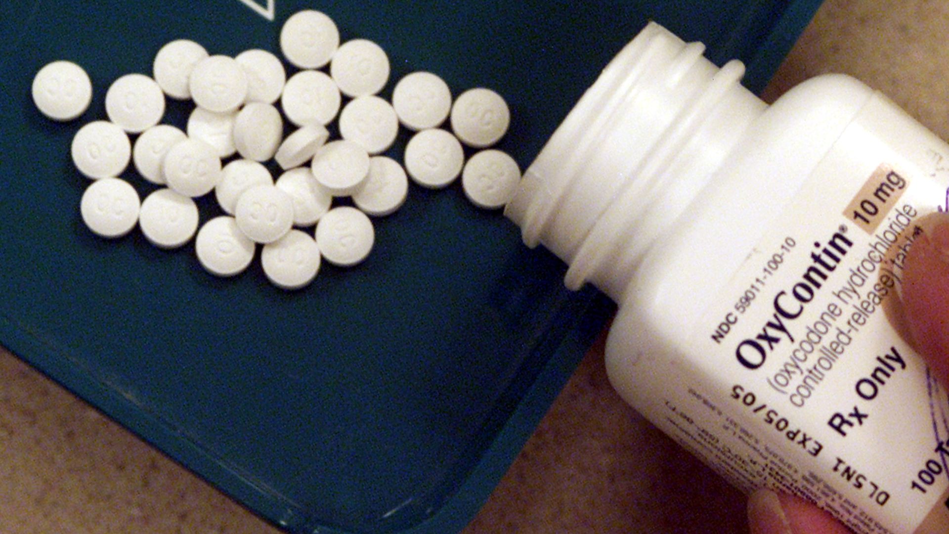 In this image, small white round pills spill out of a white bottle.