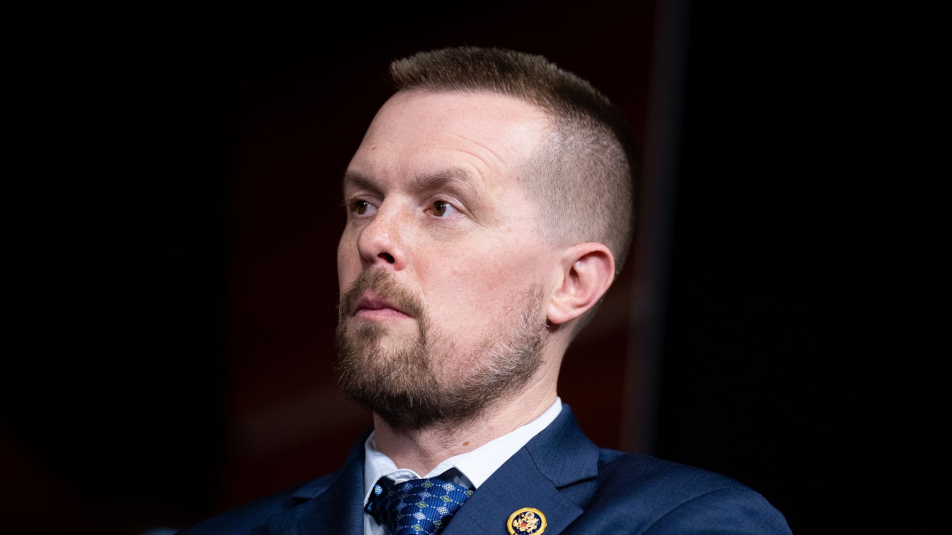 Rep. Jared Golden, wearing a blue suit against a dark backdrop.