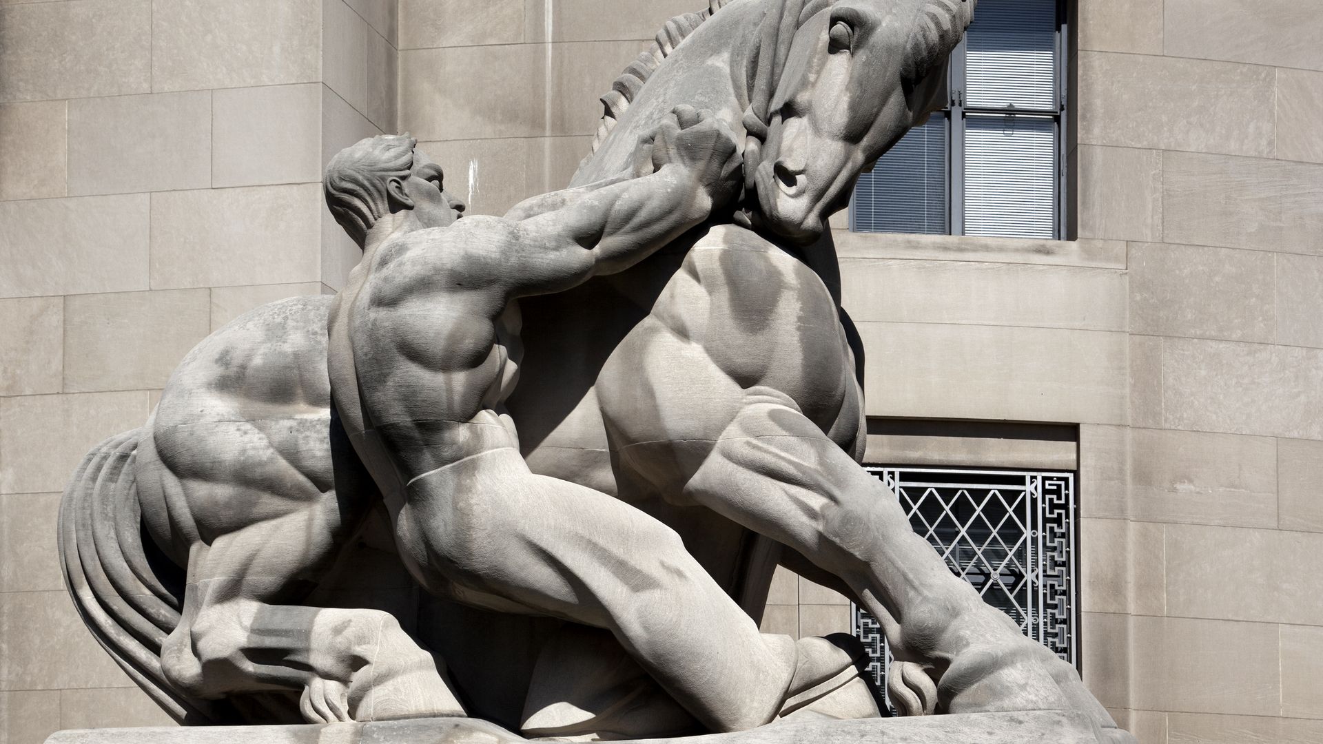 Statue of man restraining horse